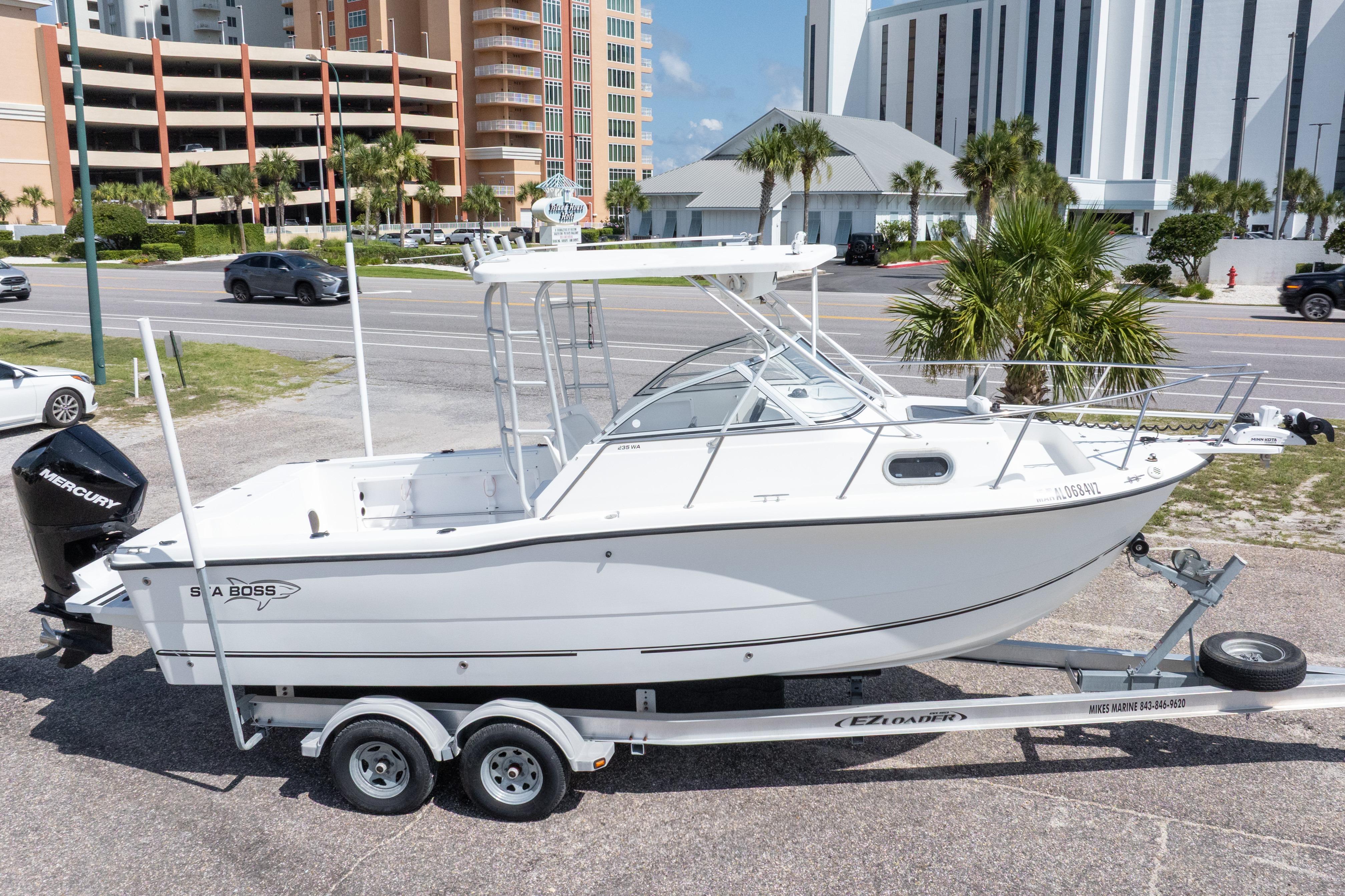 2007 Sea Boss 235 Walkaround boat on trailer, parked near road with buildings in background.