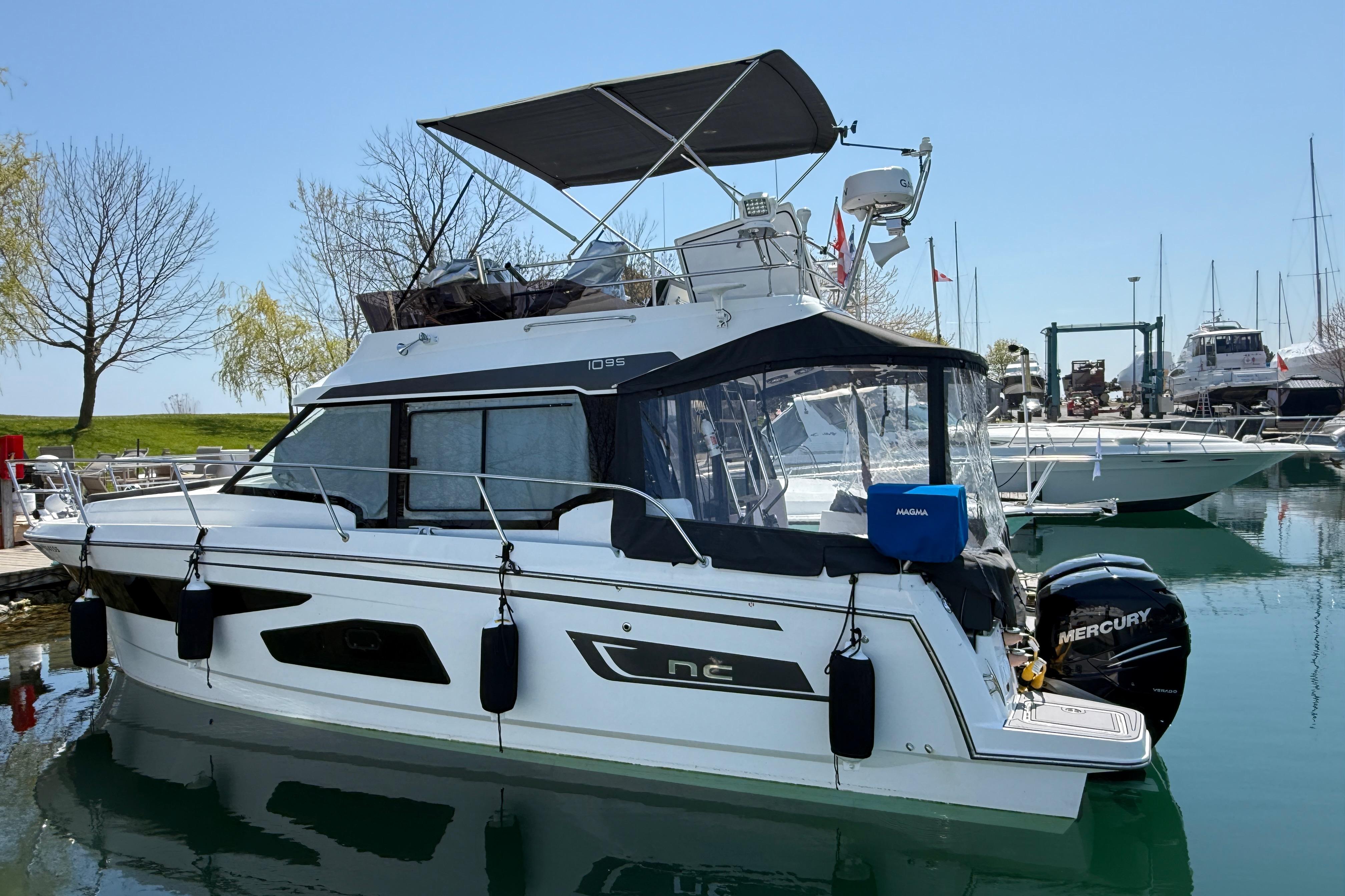 2022 Jeanneau NC 1095 Fly yacht docked in a marina, featuring sleek design and Mercury outboard engine.