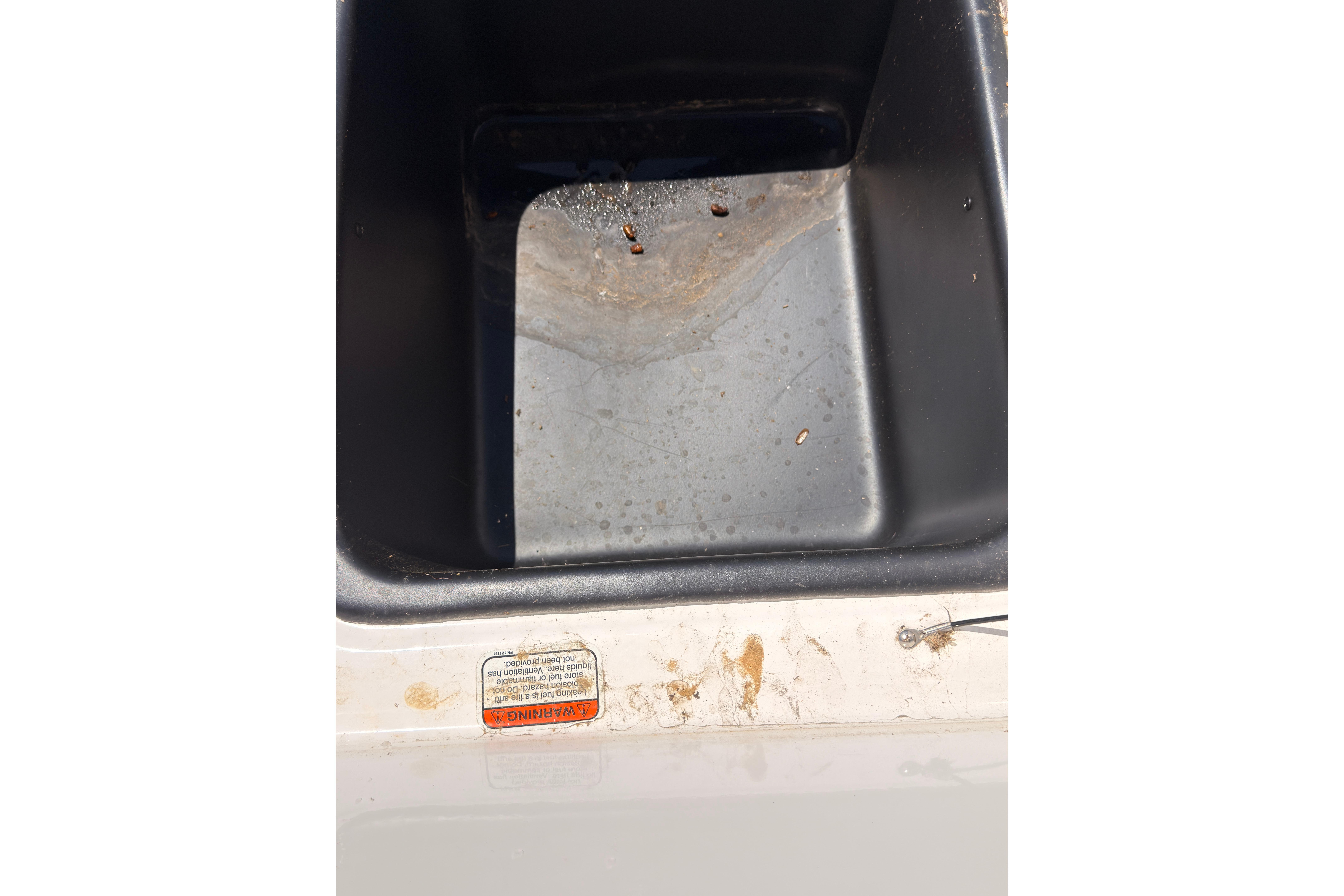 Dirty compartment of a 2022 Tahoe T18 boat with visible warning label.