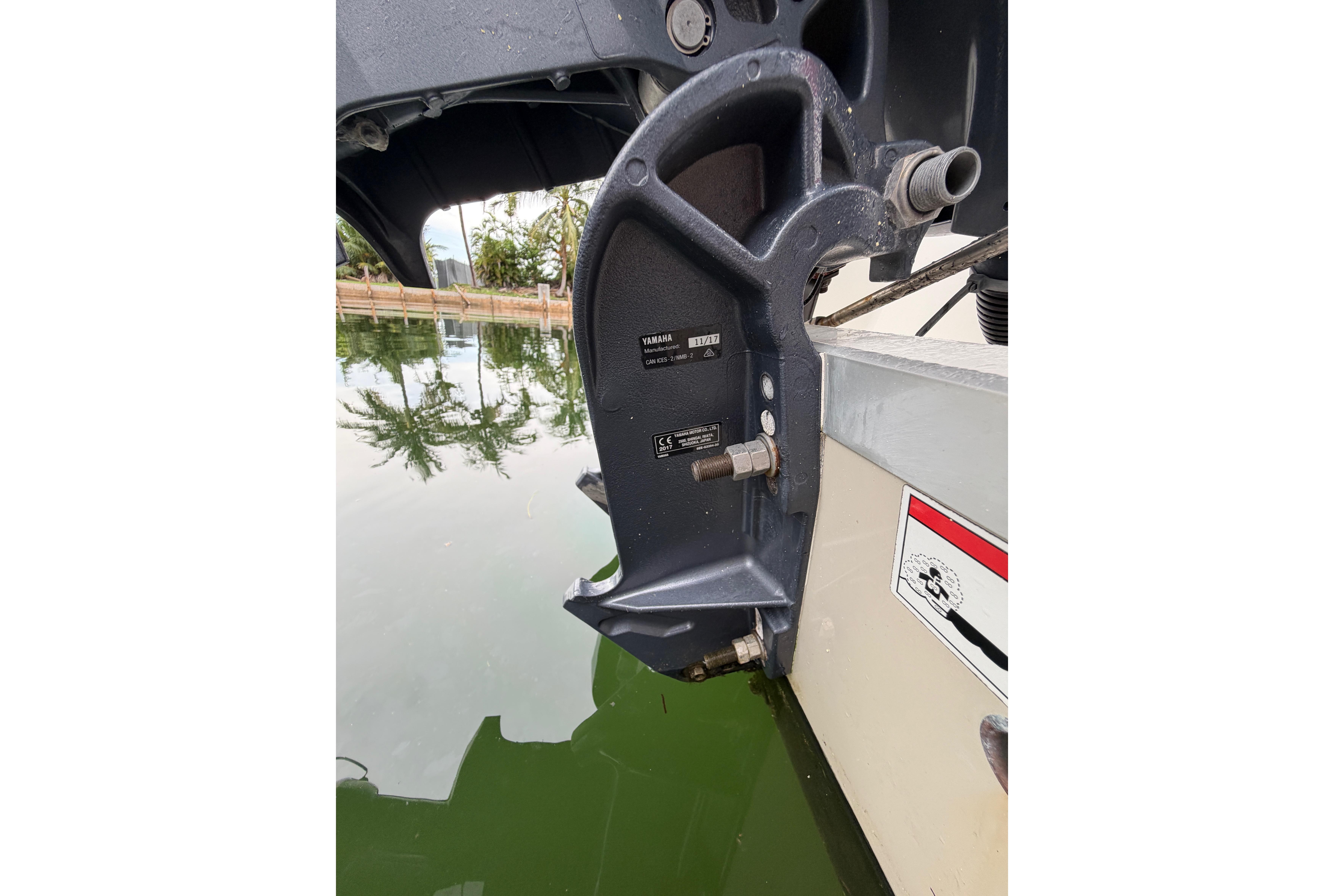 Outboard motor mount on 2019 World Cat 230 DC, near water with palm tree reflections.