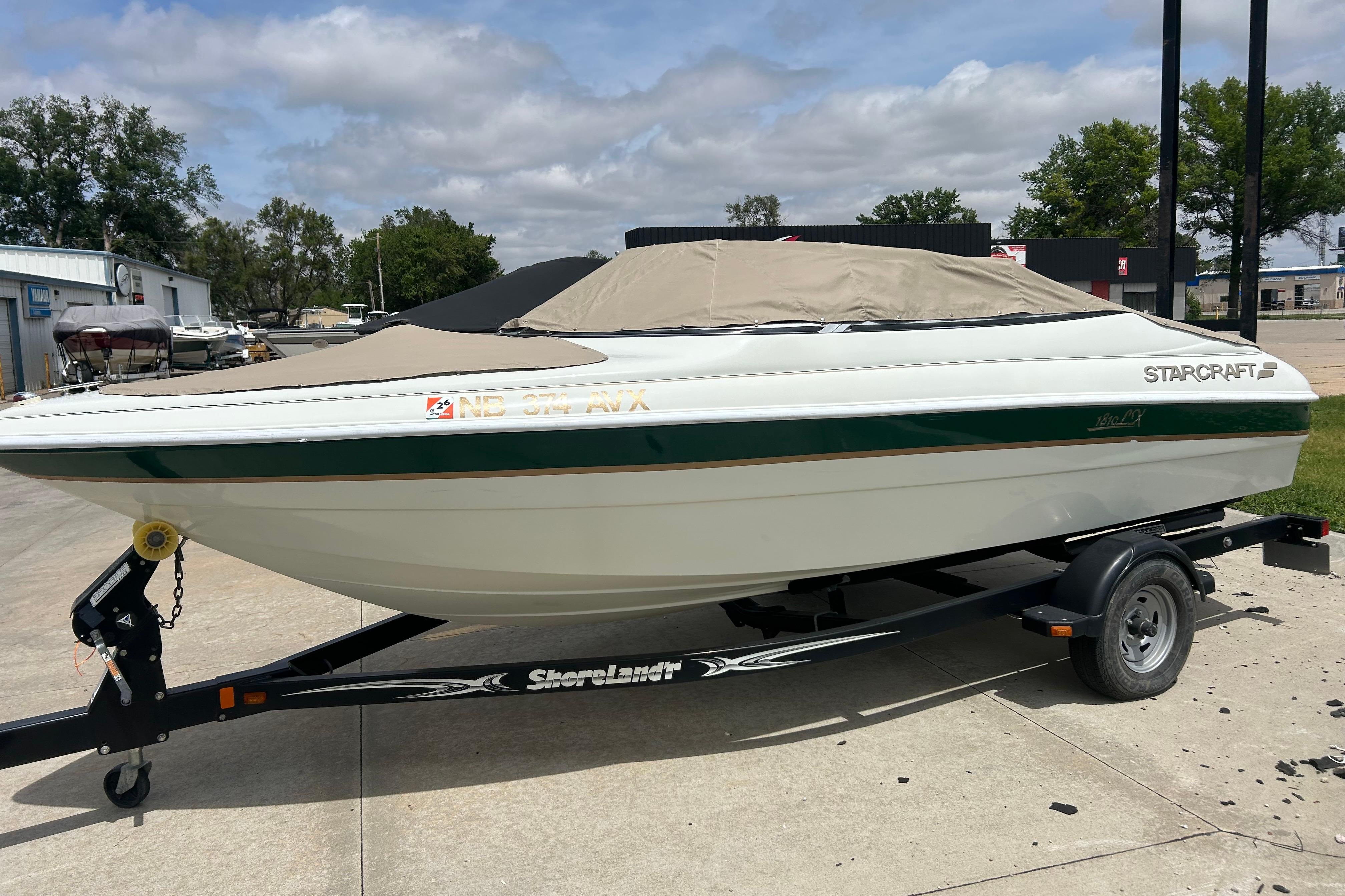 2000 Starcraft 1810 boat on trailer, covered, parked outdoors on a sunny day.