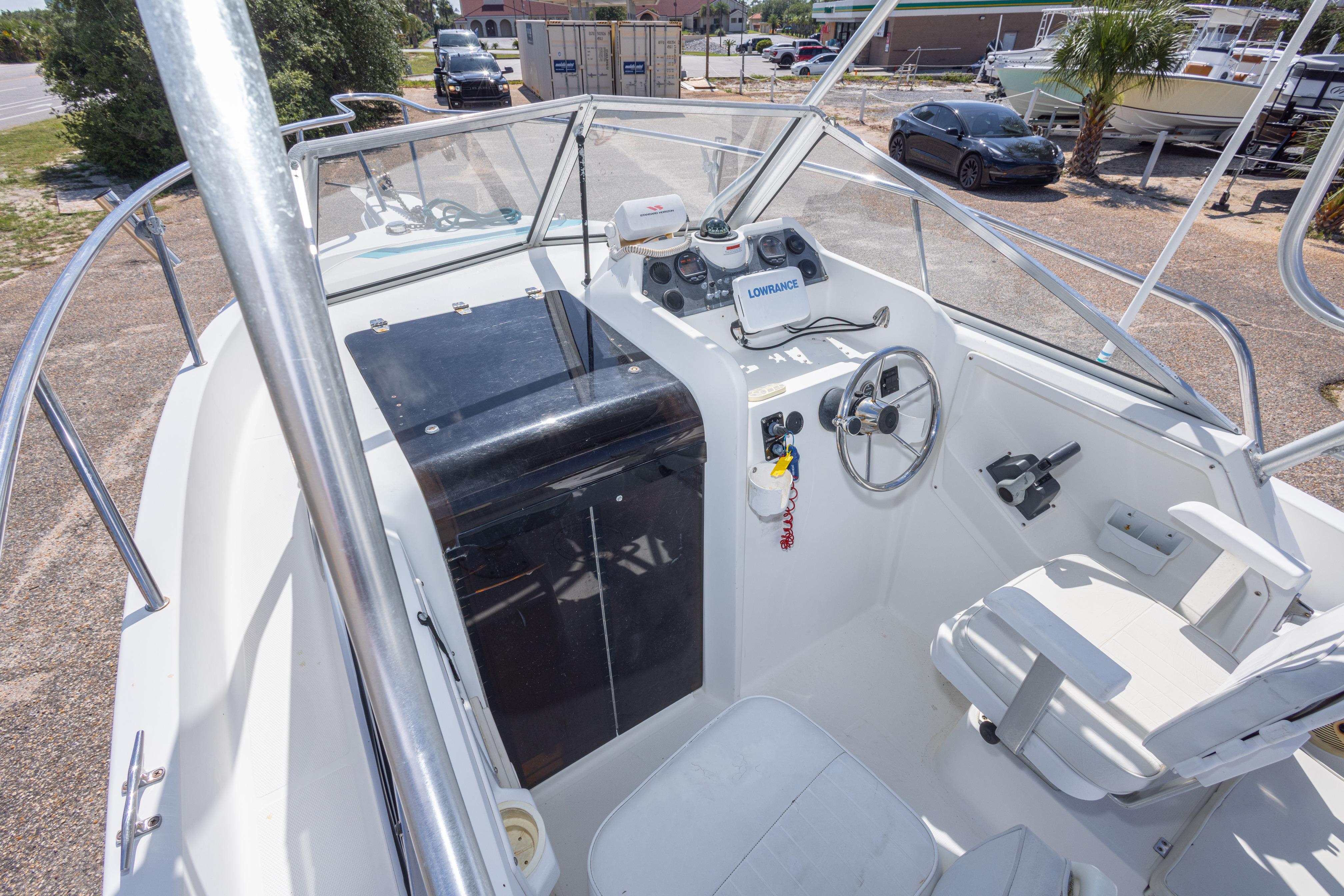 1999 Aquasport 225 Explorer boat cockpit with steering wheel and navigation equipment.