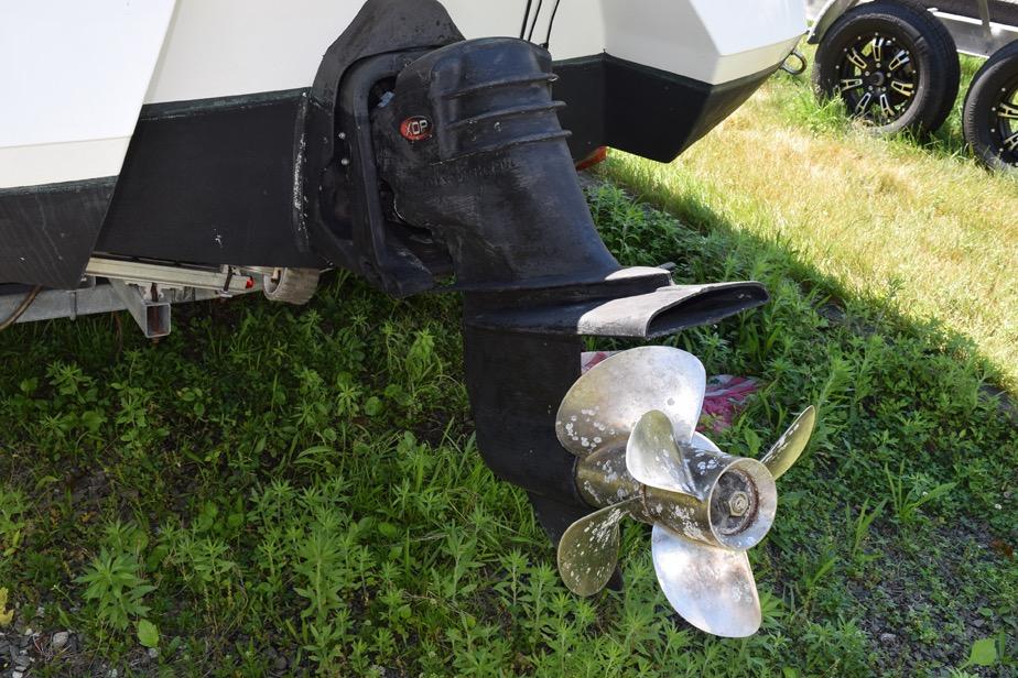 Close-up of a 2006 Cobalt 240 boat propeller and outdrive on grass.