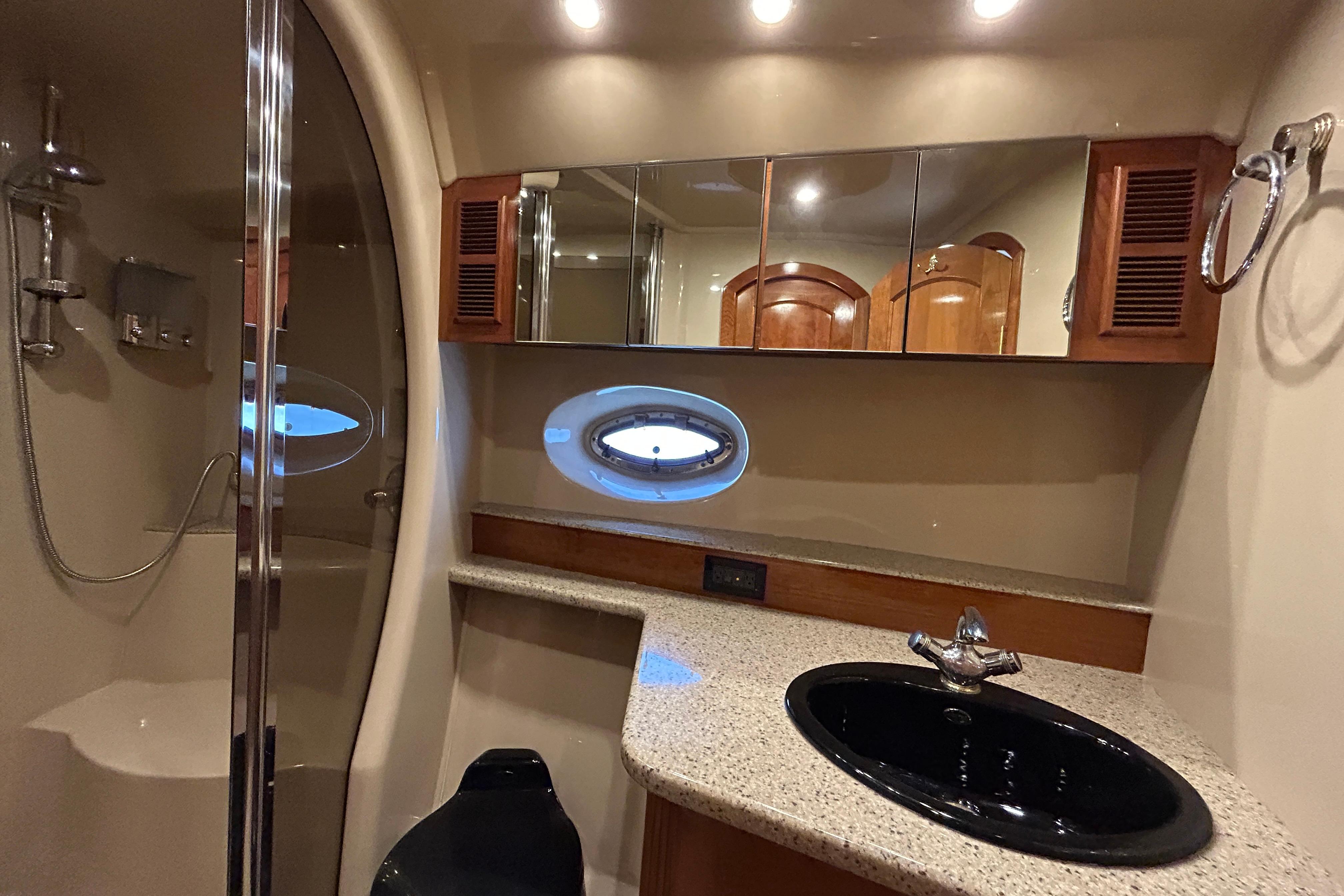 Luxurious bathroom in 2003 Cruisers Yachts 540 Express with modern fixtures and porthole window.