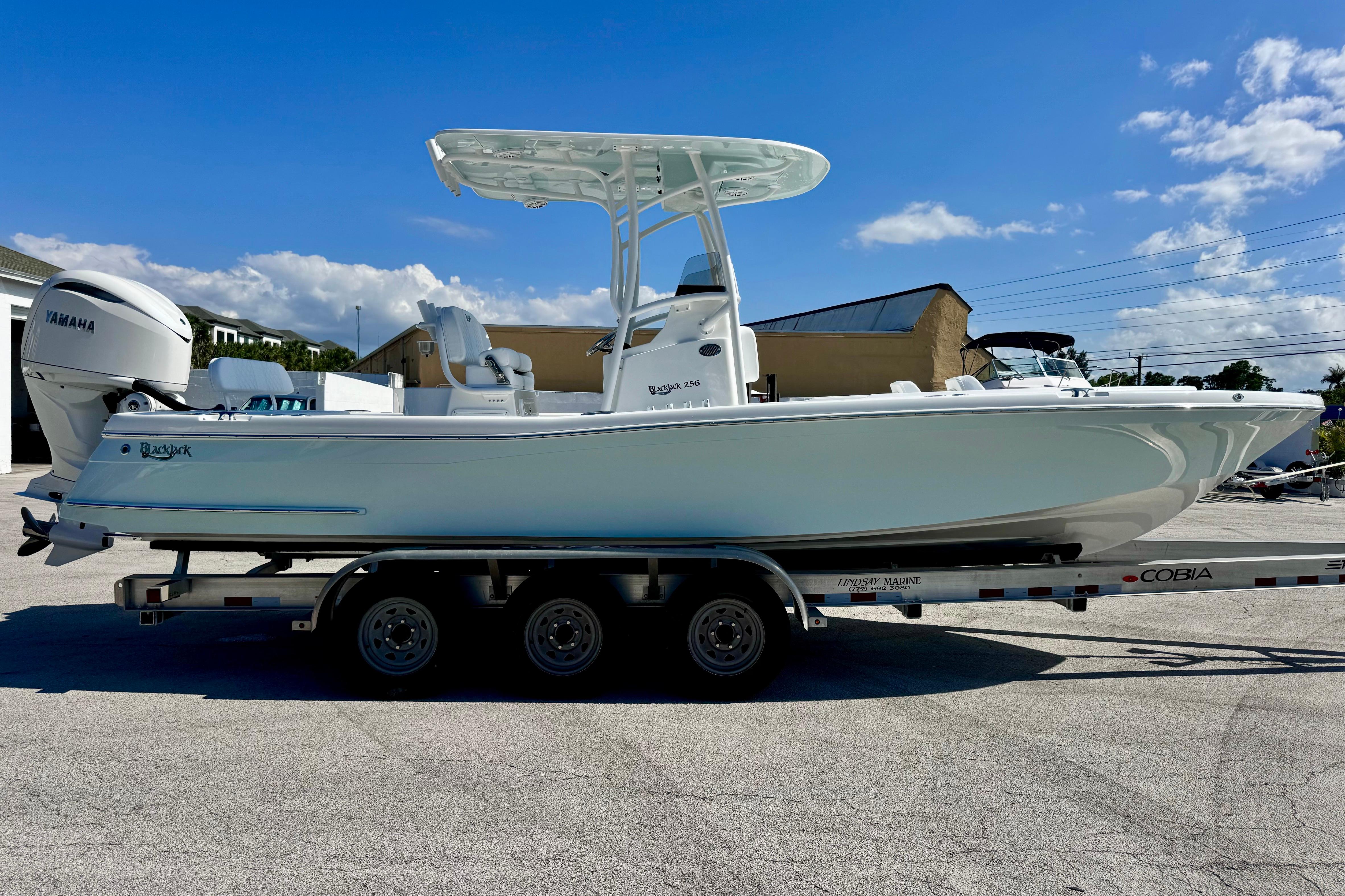 2026 BlackJack 256 Coastal boat on trailer, featuring Yamaha engine, under clear blue sky.
