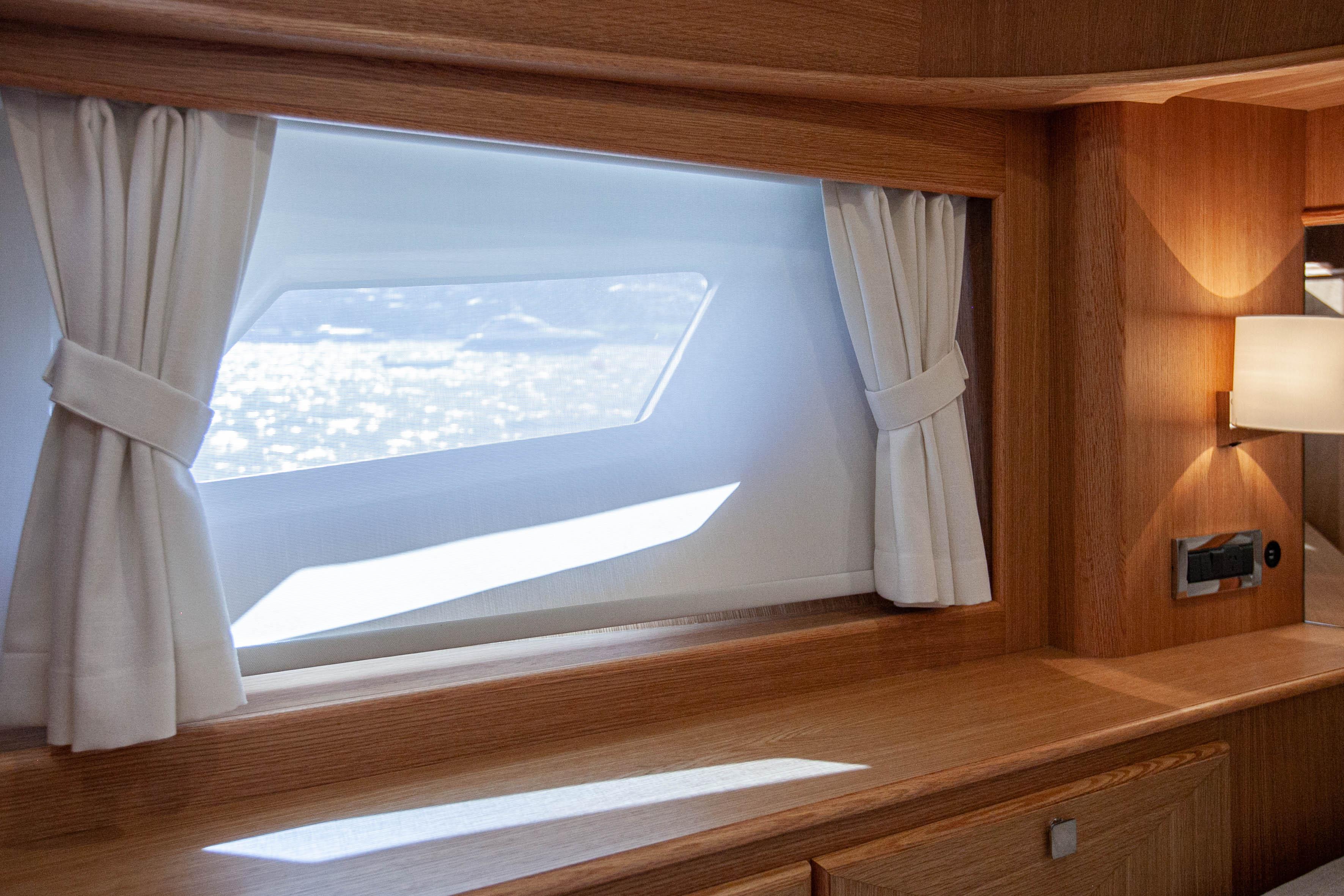 Interior of 2023 Vicem 55 yacht with elegant wood finish and window curtains.