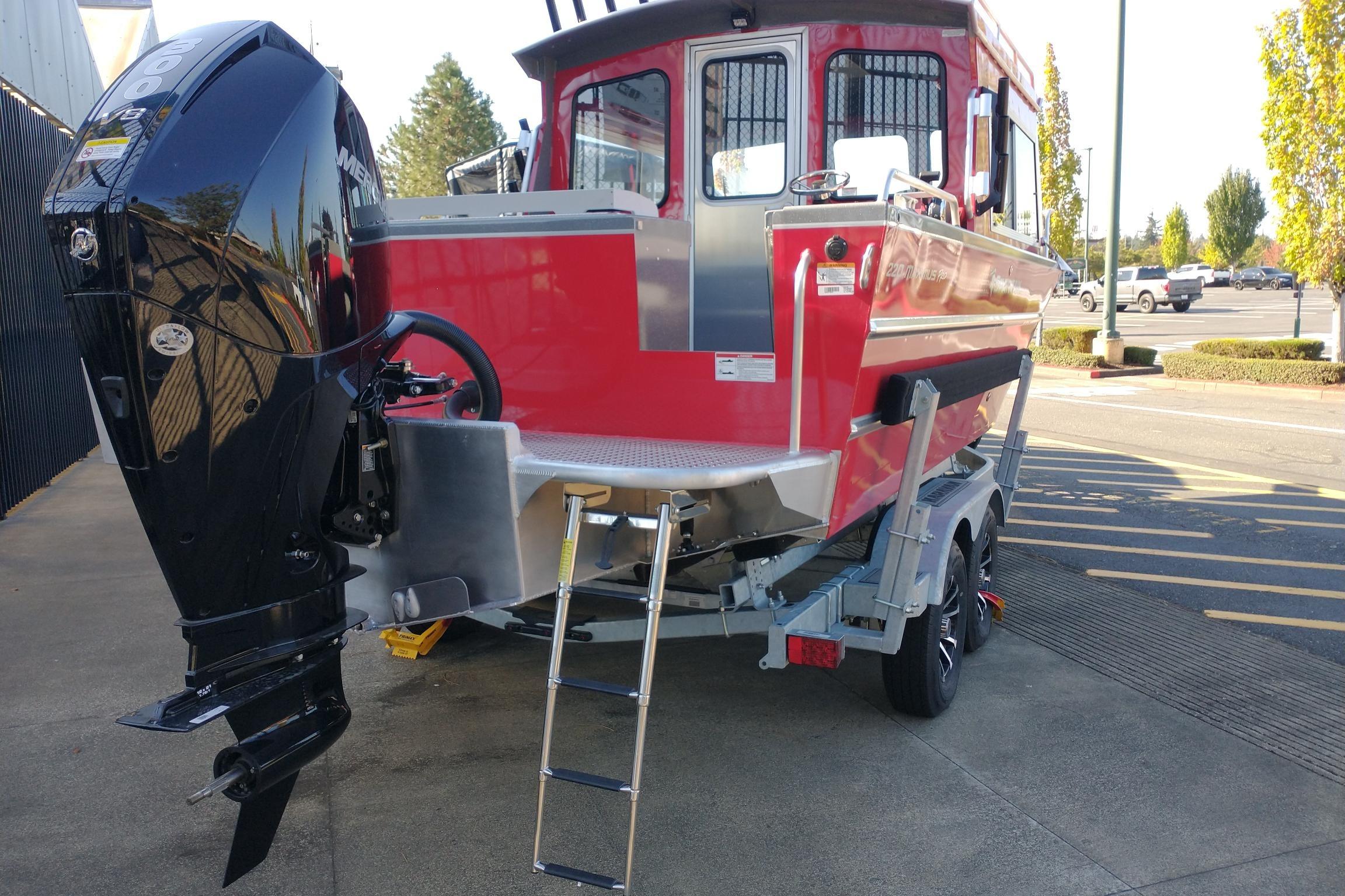 2024 Spartan 220 Maximus Pro boat with outboard motor and trailer in a parking lot.