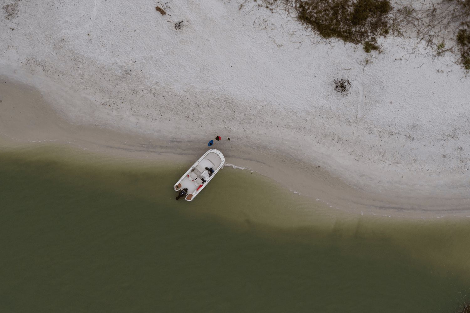 Aerial view of a boat on a sandy shore with calm water.