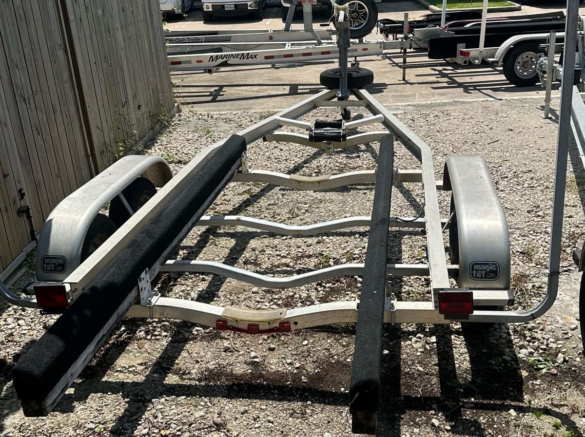 A boat trailer is parked on a gravel lot, surrounded by other trailers.