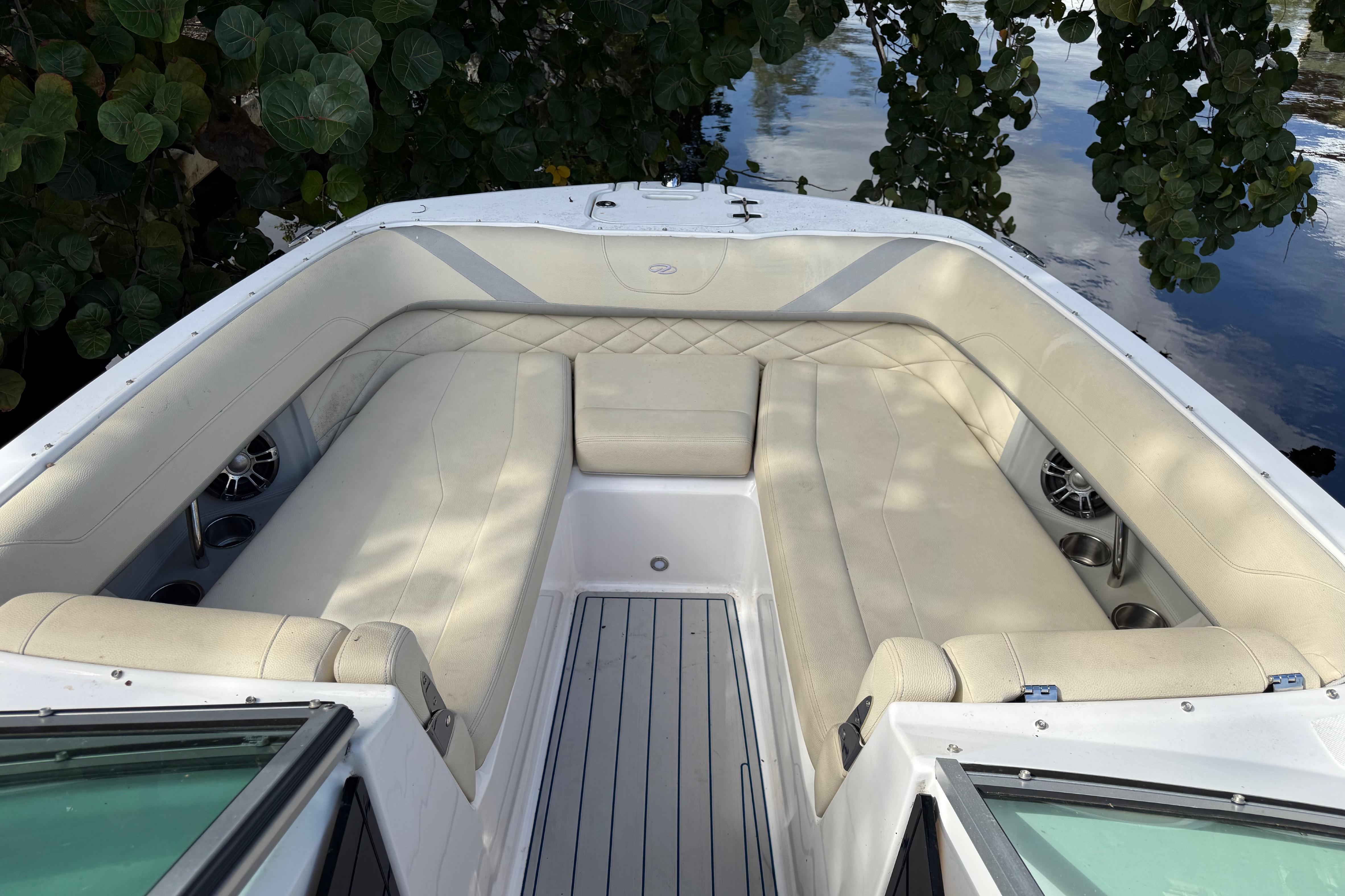 Luxurious seating area on a 2021 Regal 26 OBX boat, surrounded by lush greenery.
