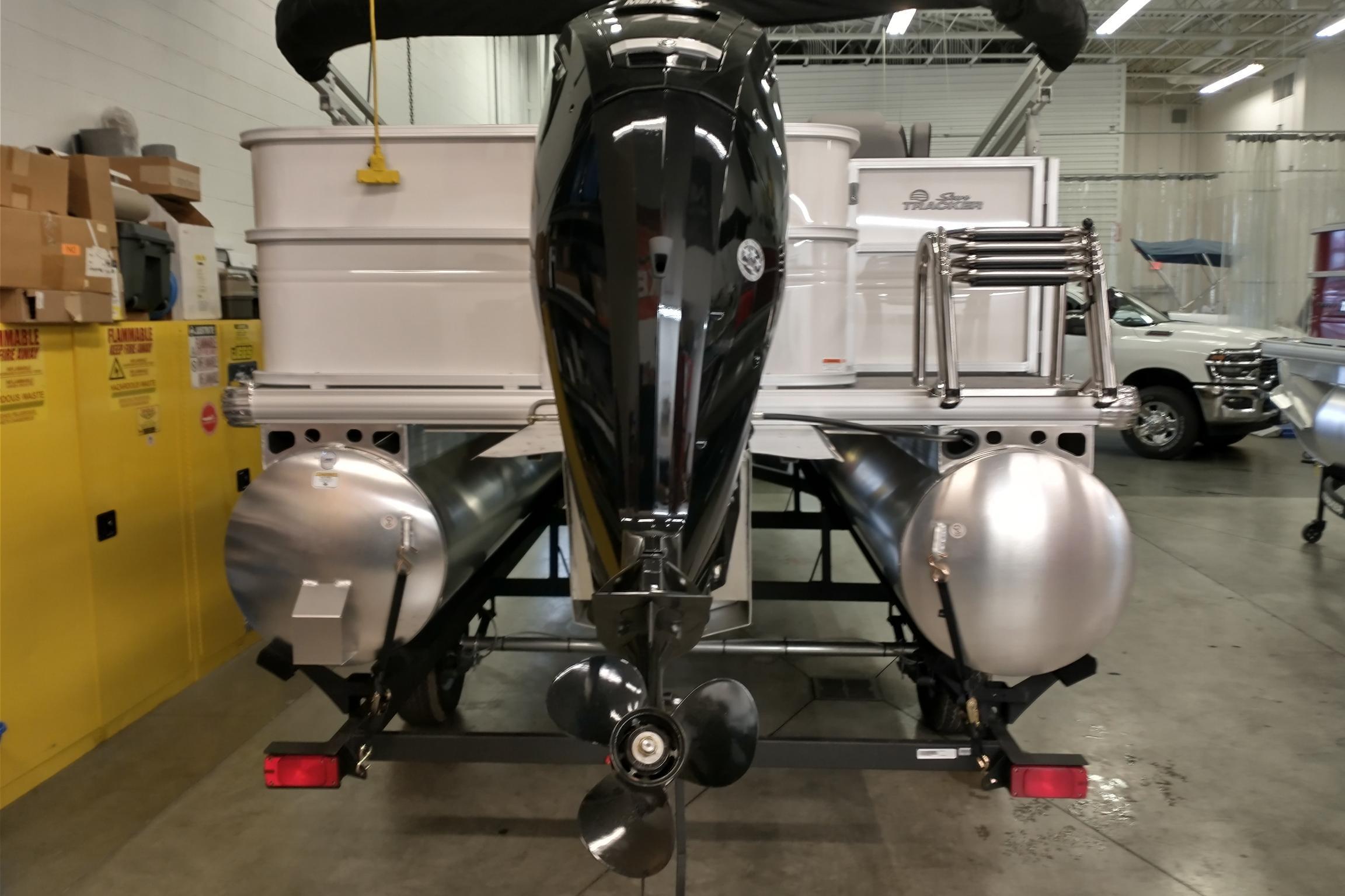 2026 Sun Tracker Party Barge 18 DLX pontoon boat in a showroom, rear view.