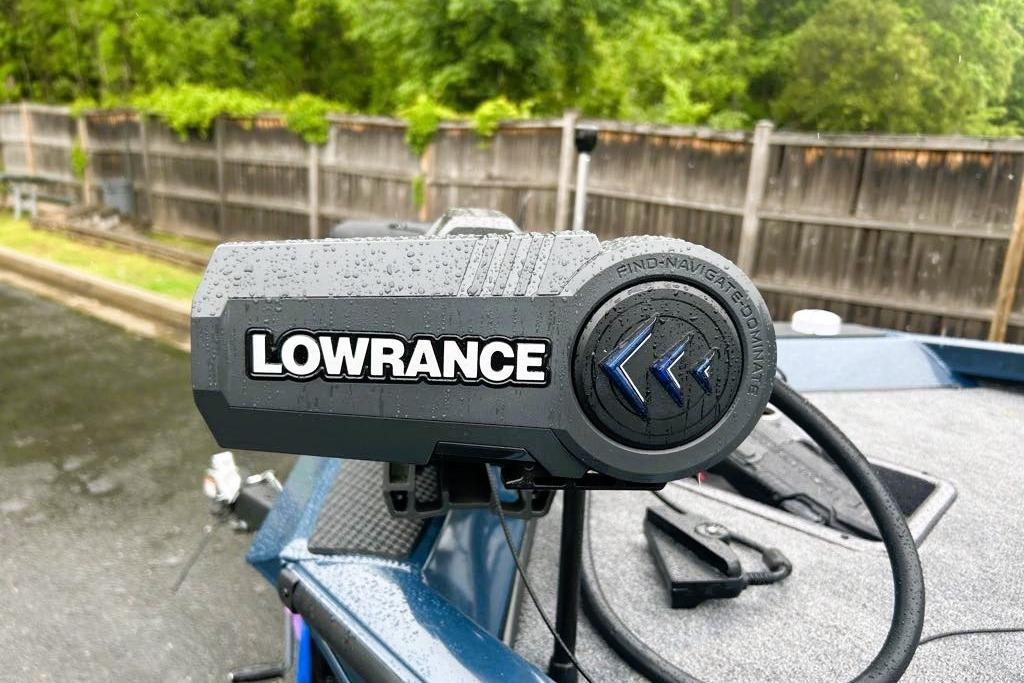 Lowrance device on 2026 Ranger RT188P boat, wet from rain, with wooden fence background.
