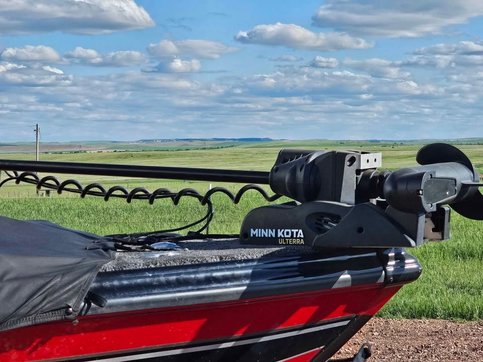 Lund 1975 Tyee boat with Minn Kota Ulterra motor on green field.