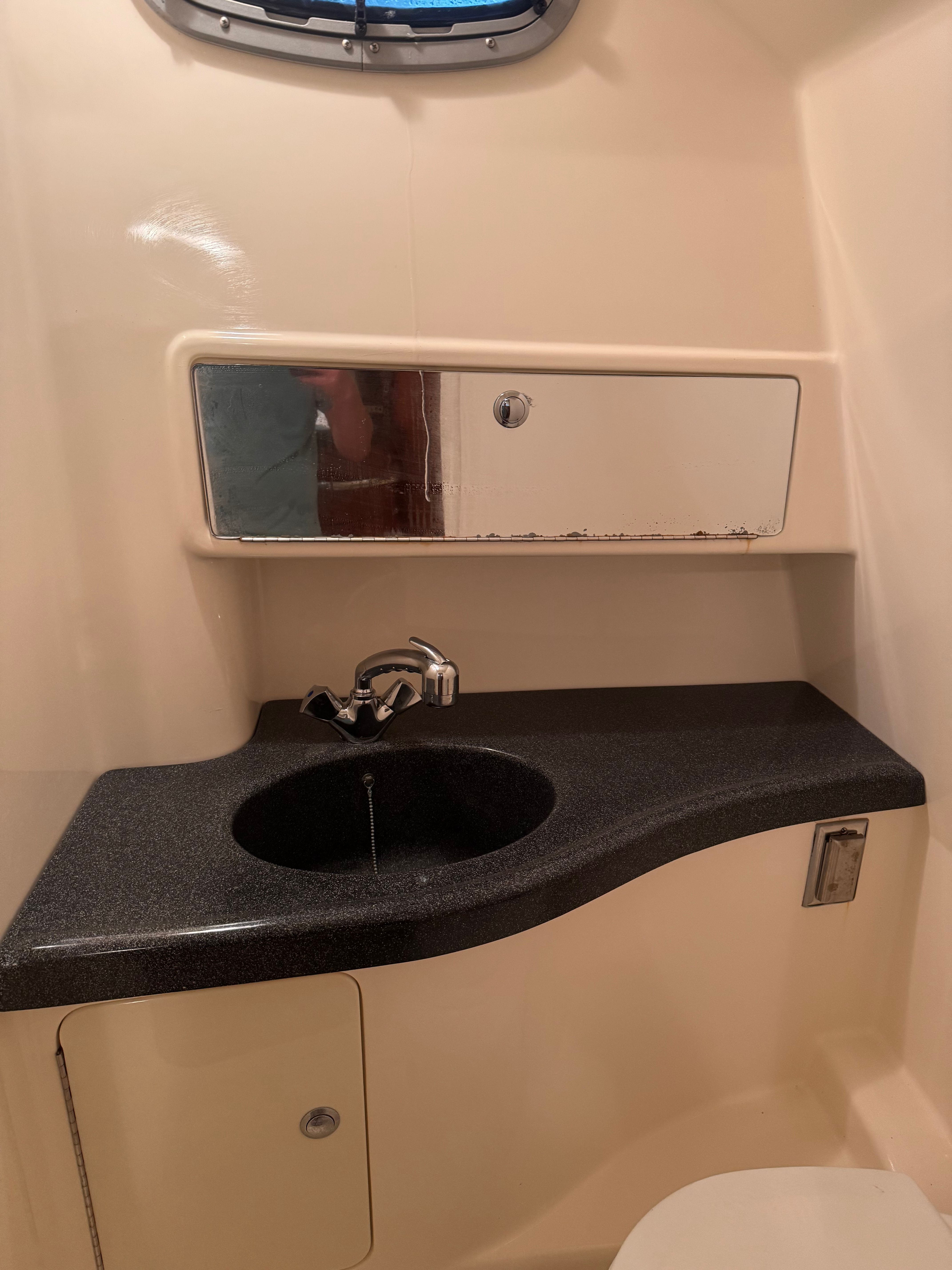 The image shows a bathroom with a sink and mirror inside a boat.
