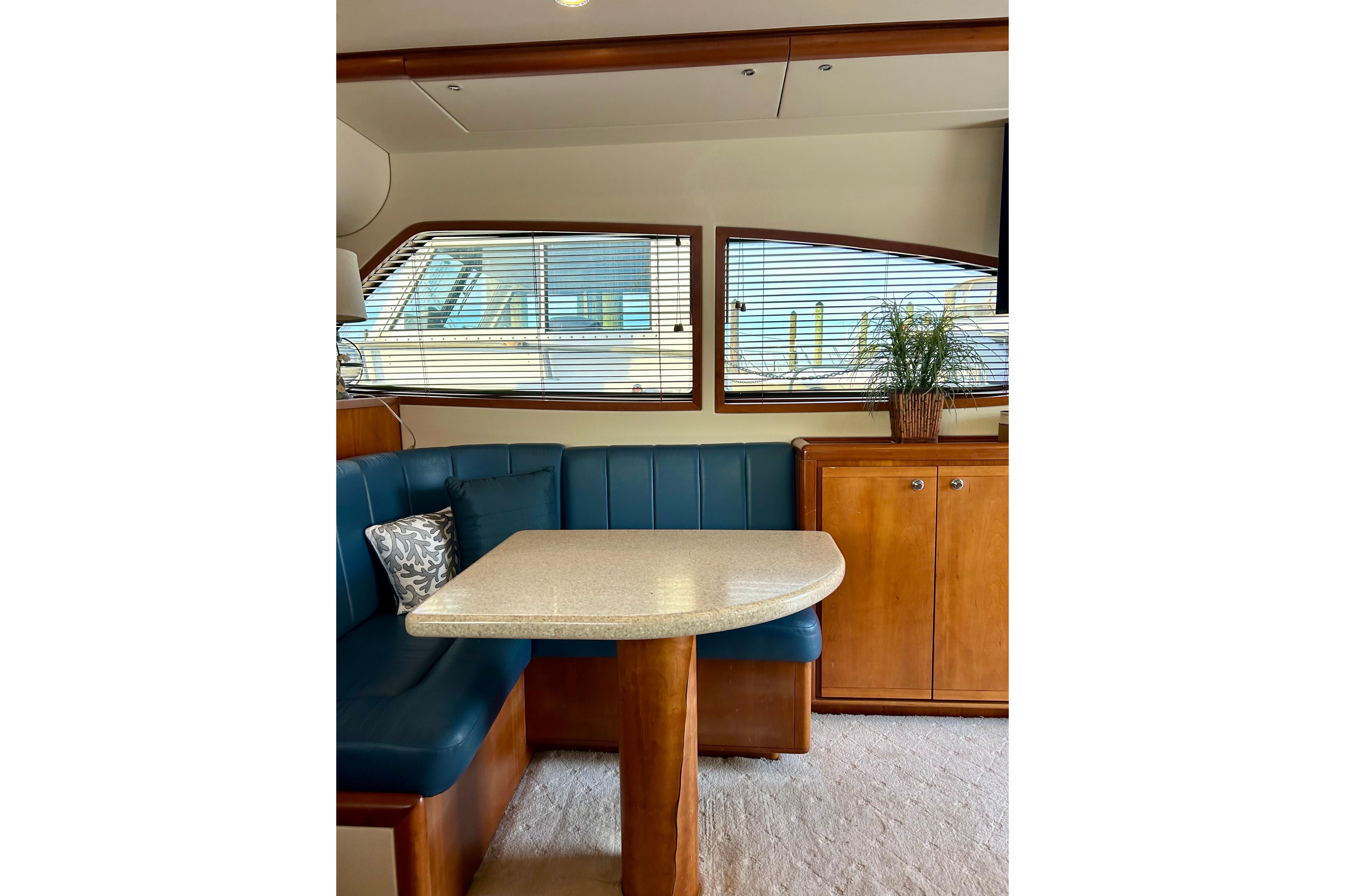 2005 Bertram 390 Convertible yacht interior with blue seating, wooden cabinetry, and a dining table.
