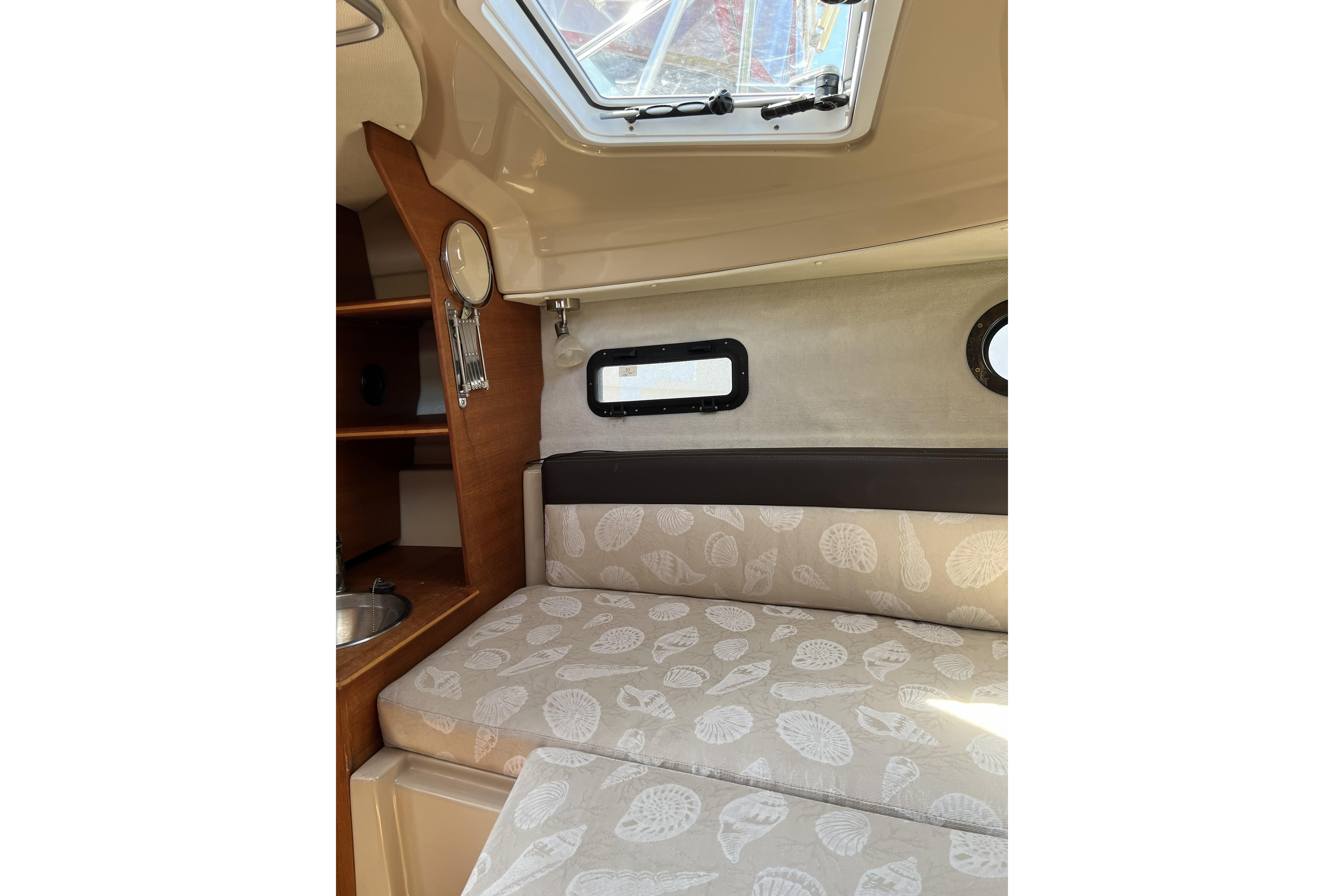 Interior cabin of 2018 Ranger Tugs R-23 with patterned cushions and porthole window.