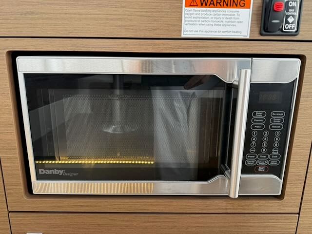 A microwave oven is built into a wooden panel, with a warning sign above.