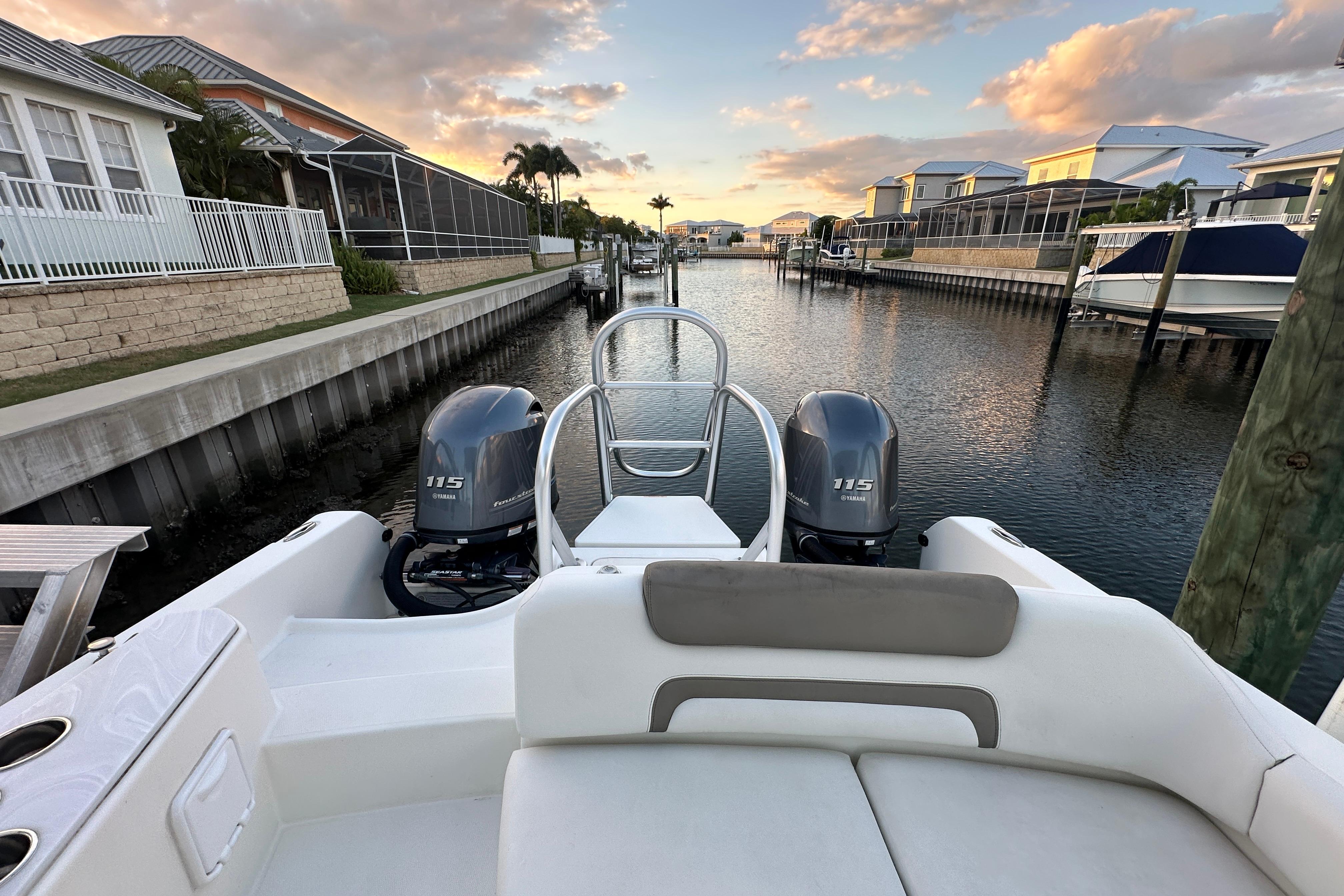 2021 World Cat 230 SD boat with twin Yamaha 115 engines docked in a canal.