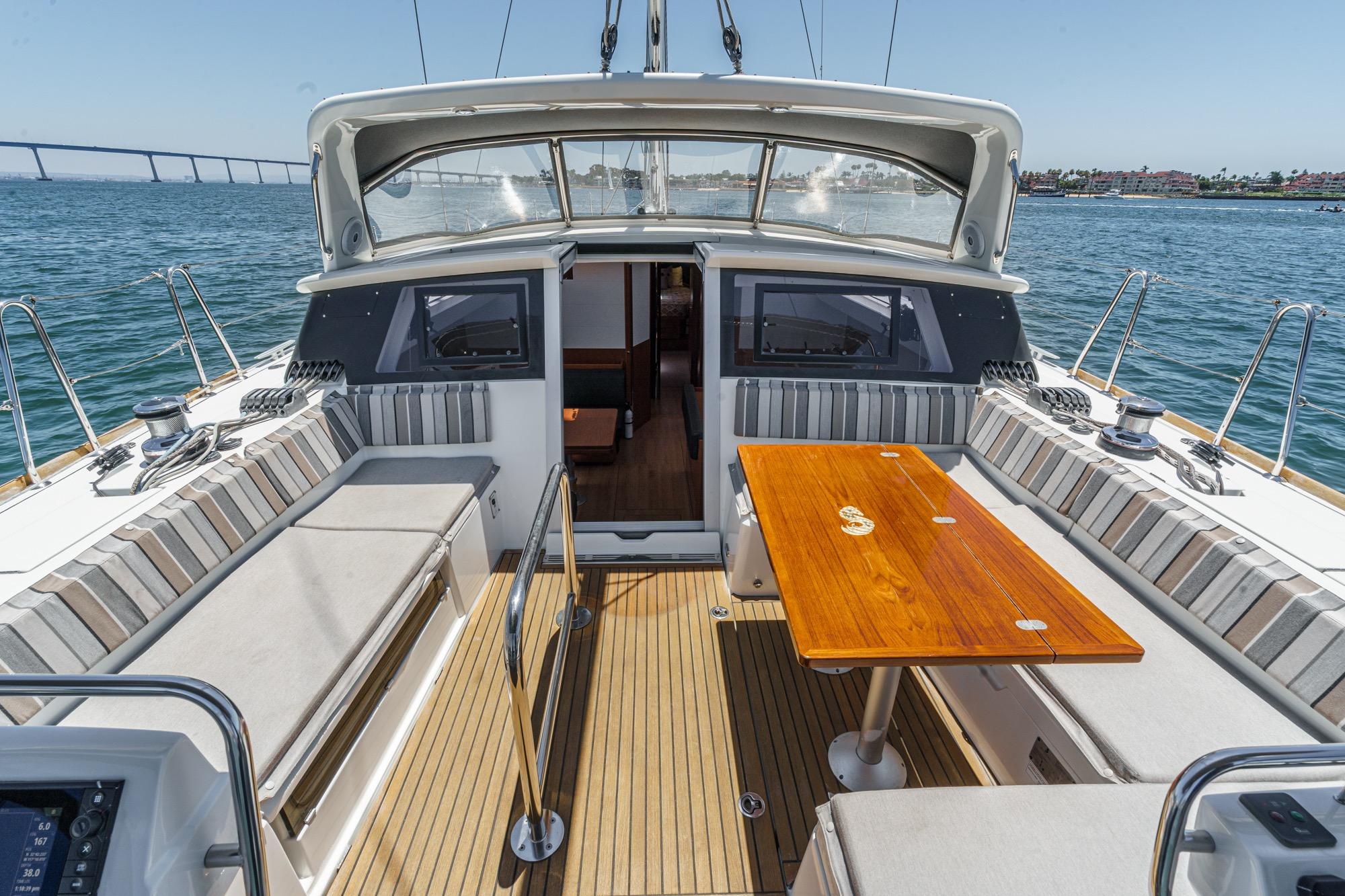 2017 Beneteau Sense 50 yacht cockpit with wooden table, striped seating, and ocean view.