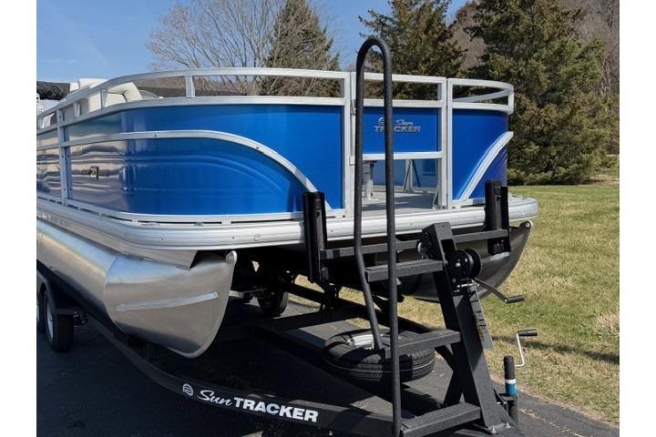2026 Sun Tracker Fishin' Barge 20 DLX pontoon boat on trailer, blue exterior.