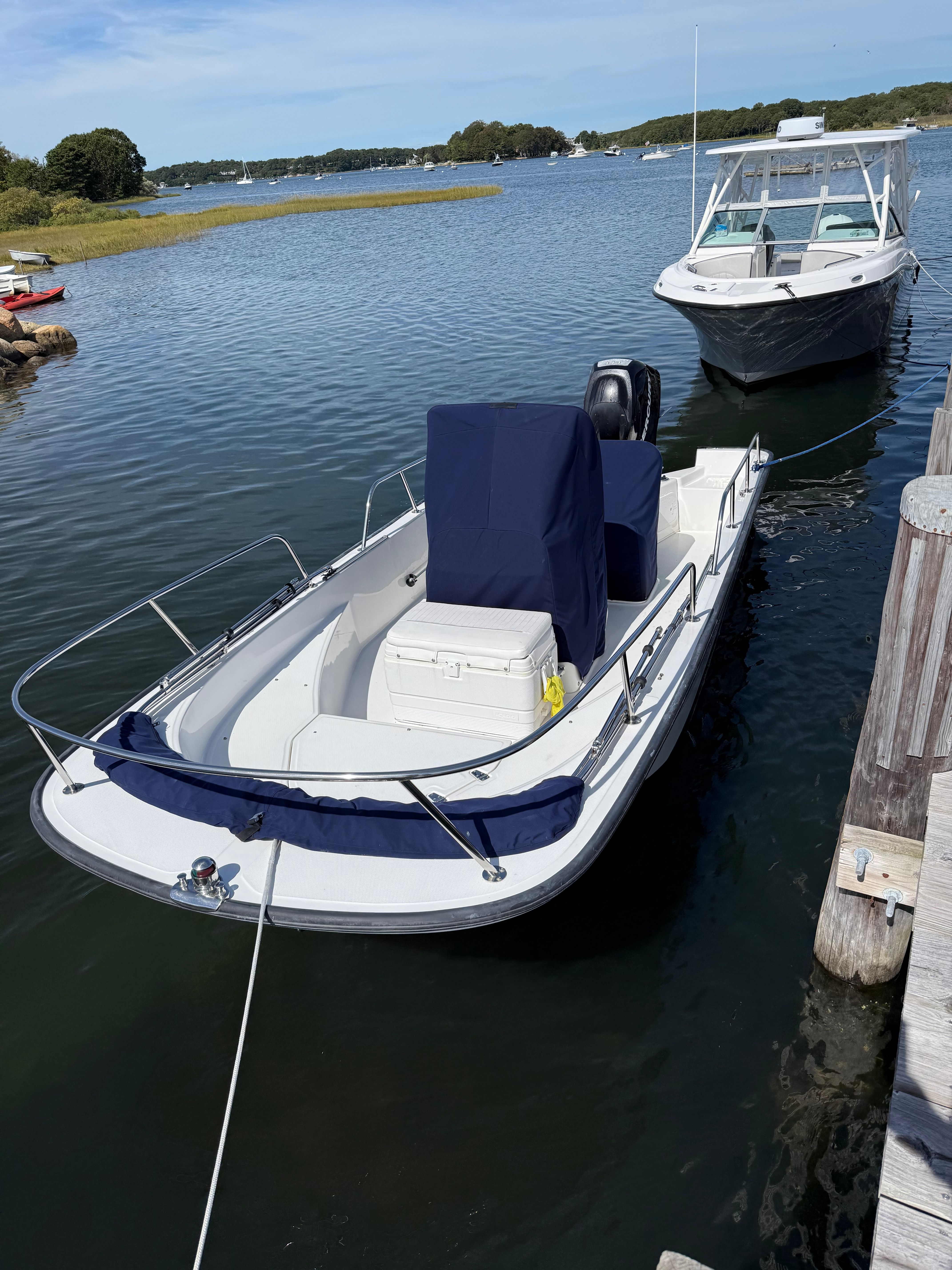 A 2011 Boston Whaler 170 Montauk docked. It's a small motorboat with a blue cover.