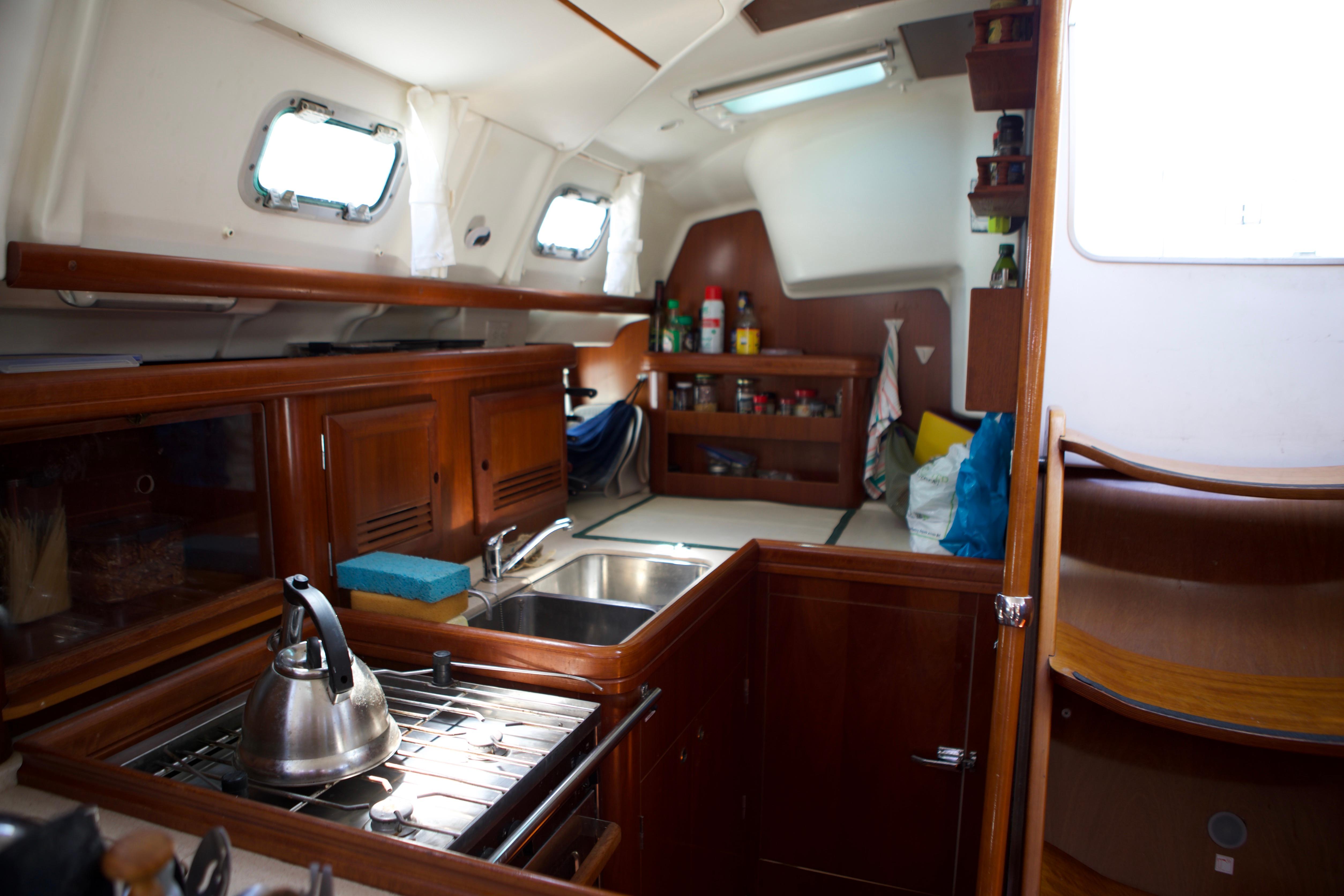 Interior of 2005 Beneteau 423 yacht kitchen with wooden cabinetry and stainless steel sink.
