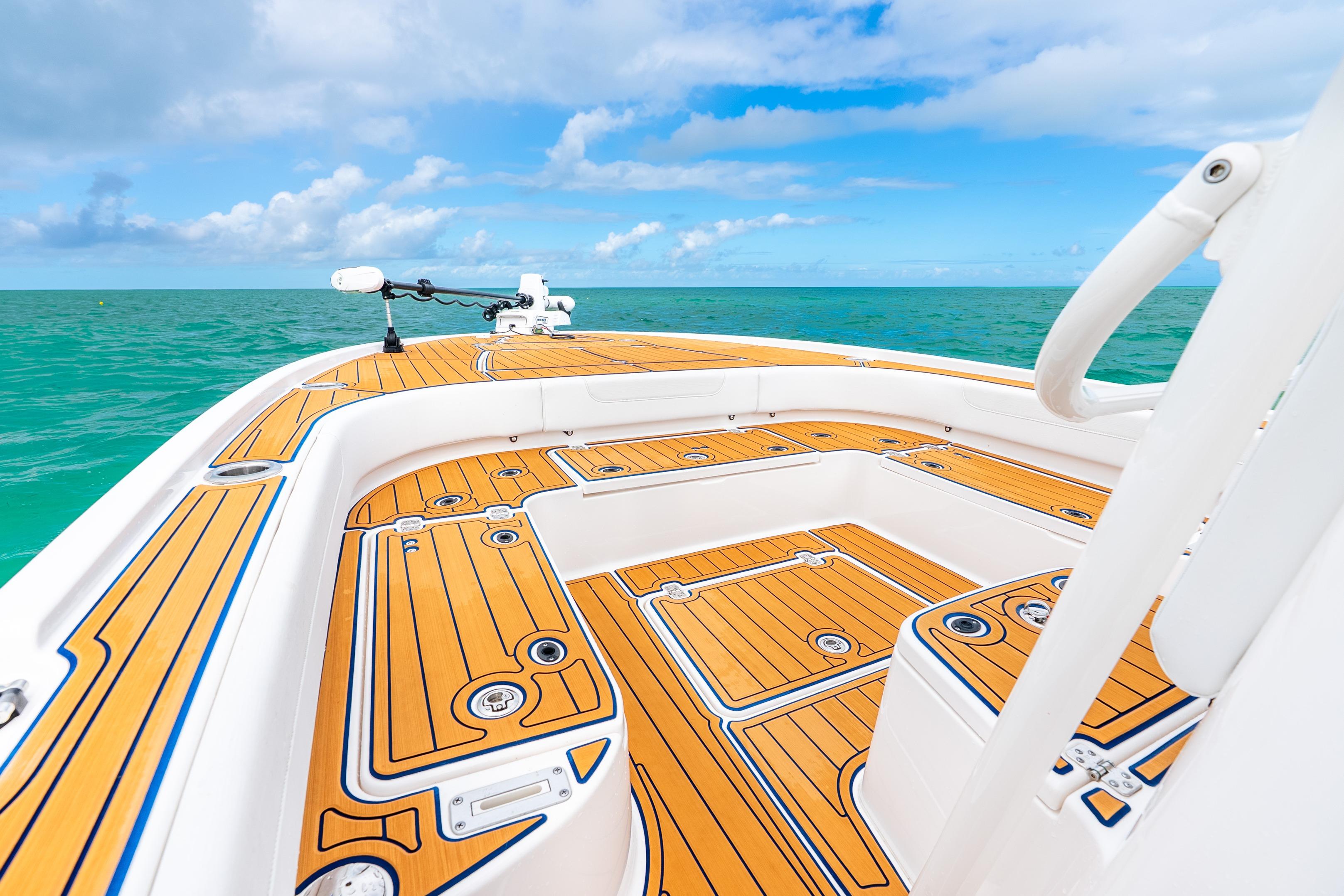 2024 Caymas 281 HB boat deck with teak flooring, ocean view, and clear blue sky.