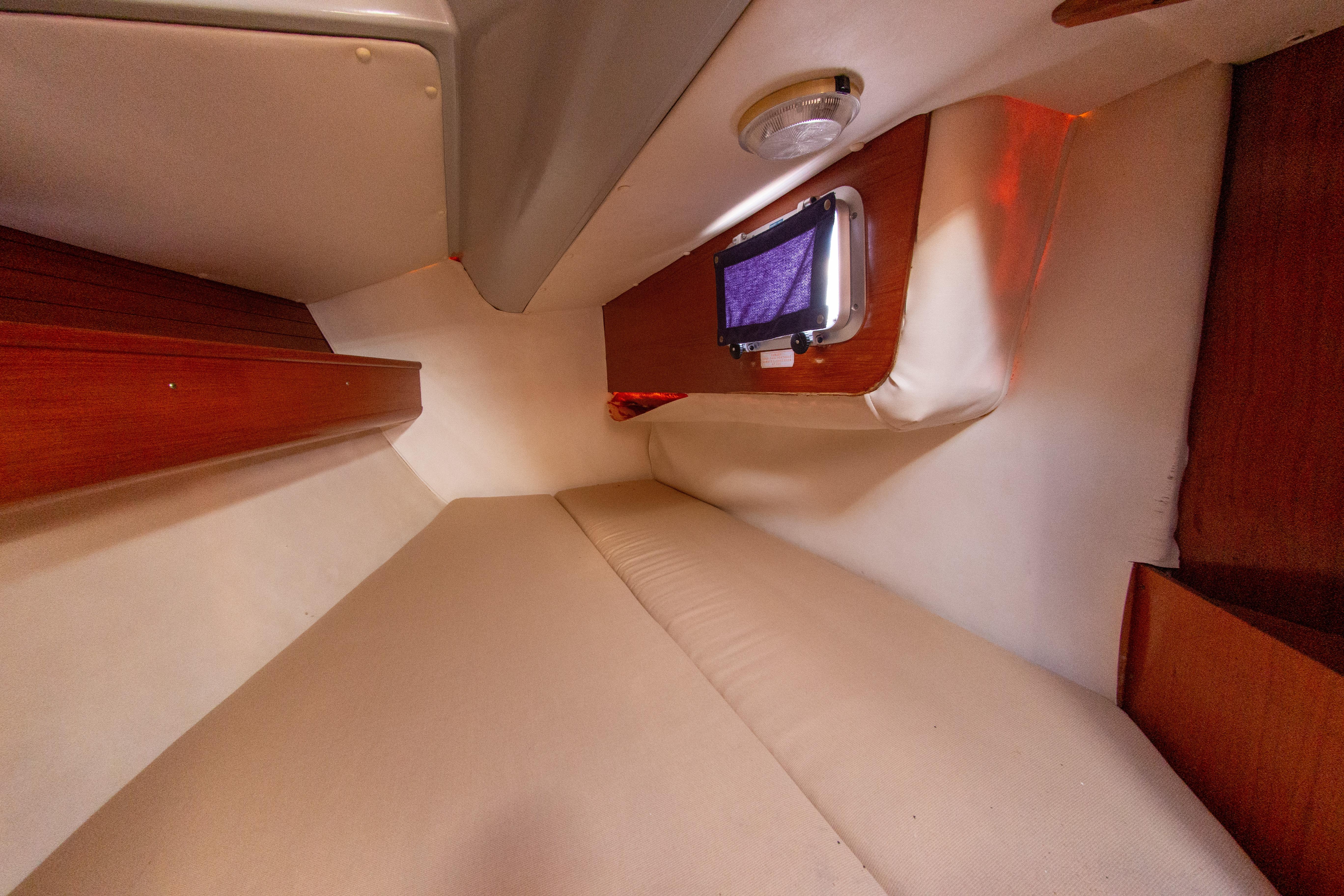 Interior cabin of 1991 Olympic Sea 42 yacht with cozy bedding and wooden accents.