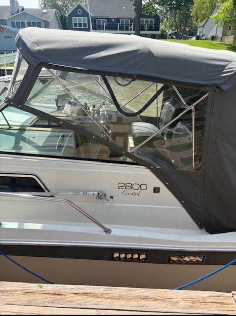 A 1986 Marinette Express boat with a black canopy, docked at a pier.
