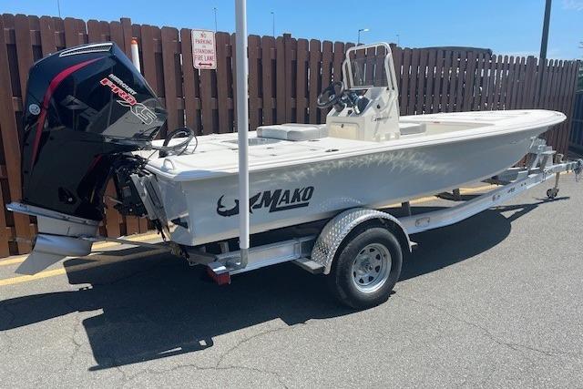 2026 Mako 18 Pro Skiff boat on trailer, parked outdoors, featuring a powerful outboard motor.