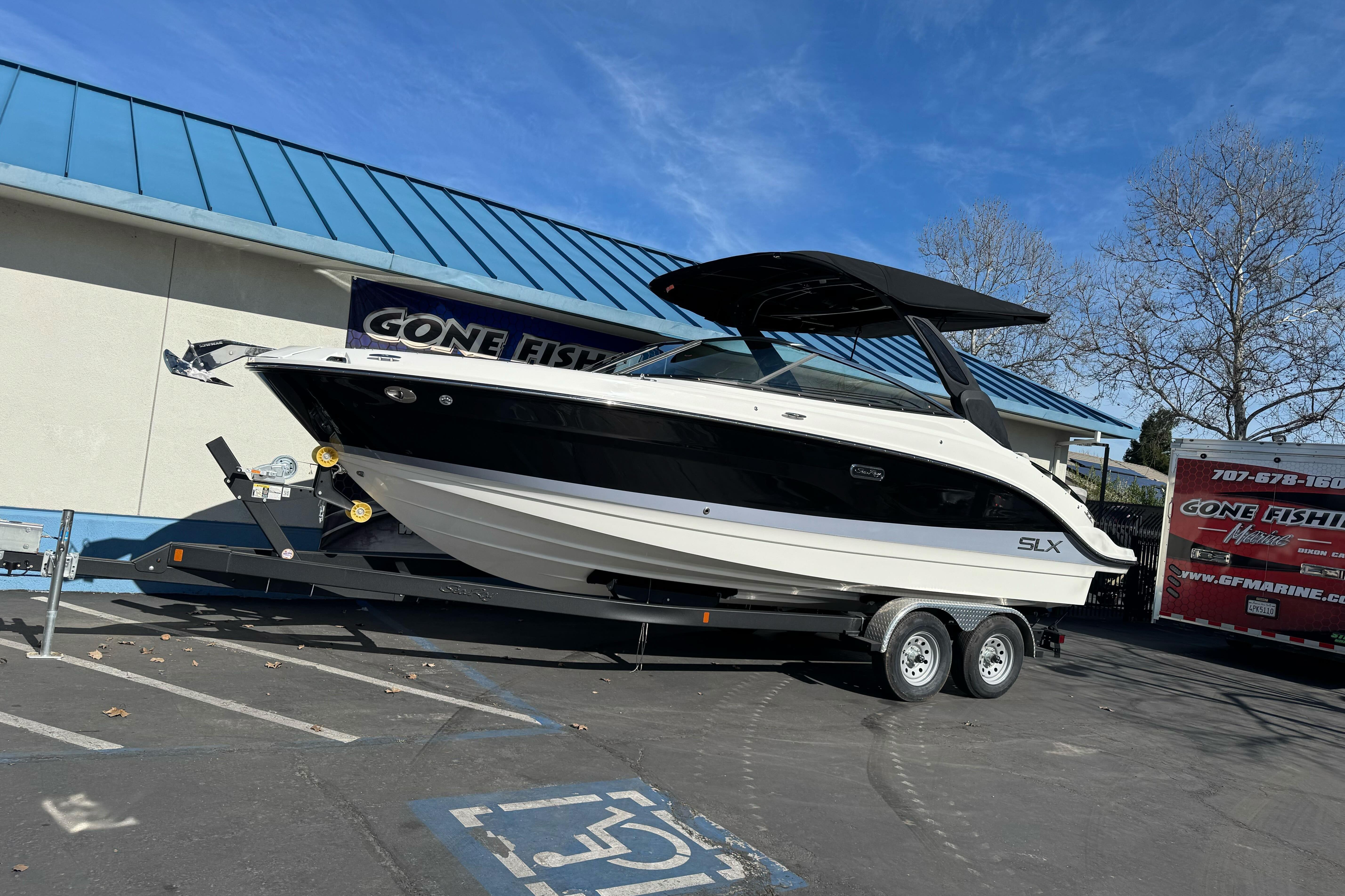 2026 Sea Ray SLX 260 boat on trailer, parked outside a building with blue roof.