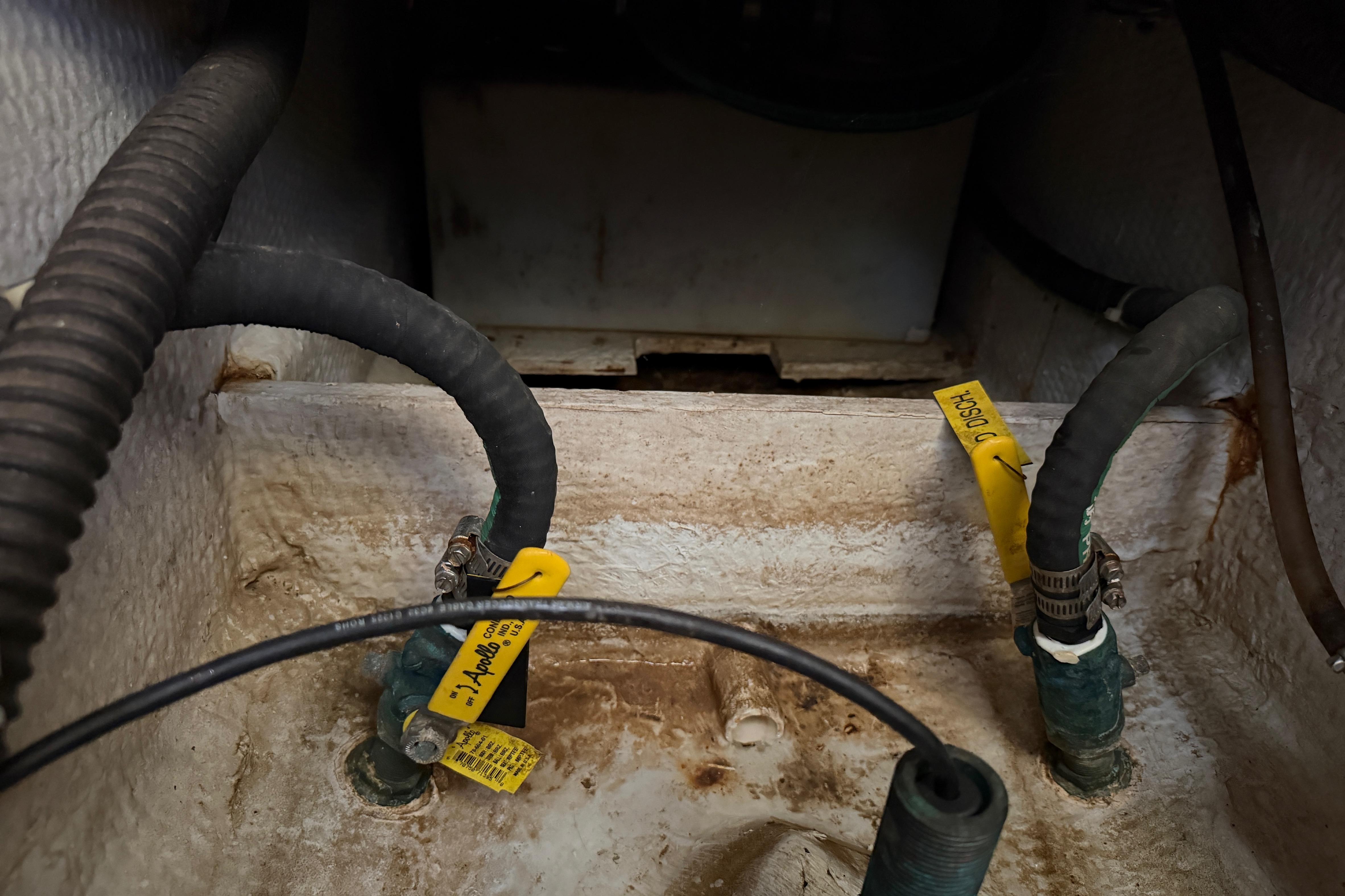 Bilge area of 2006 Grady-White Sailfish 282 with hoses and discharge labels.