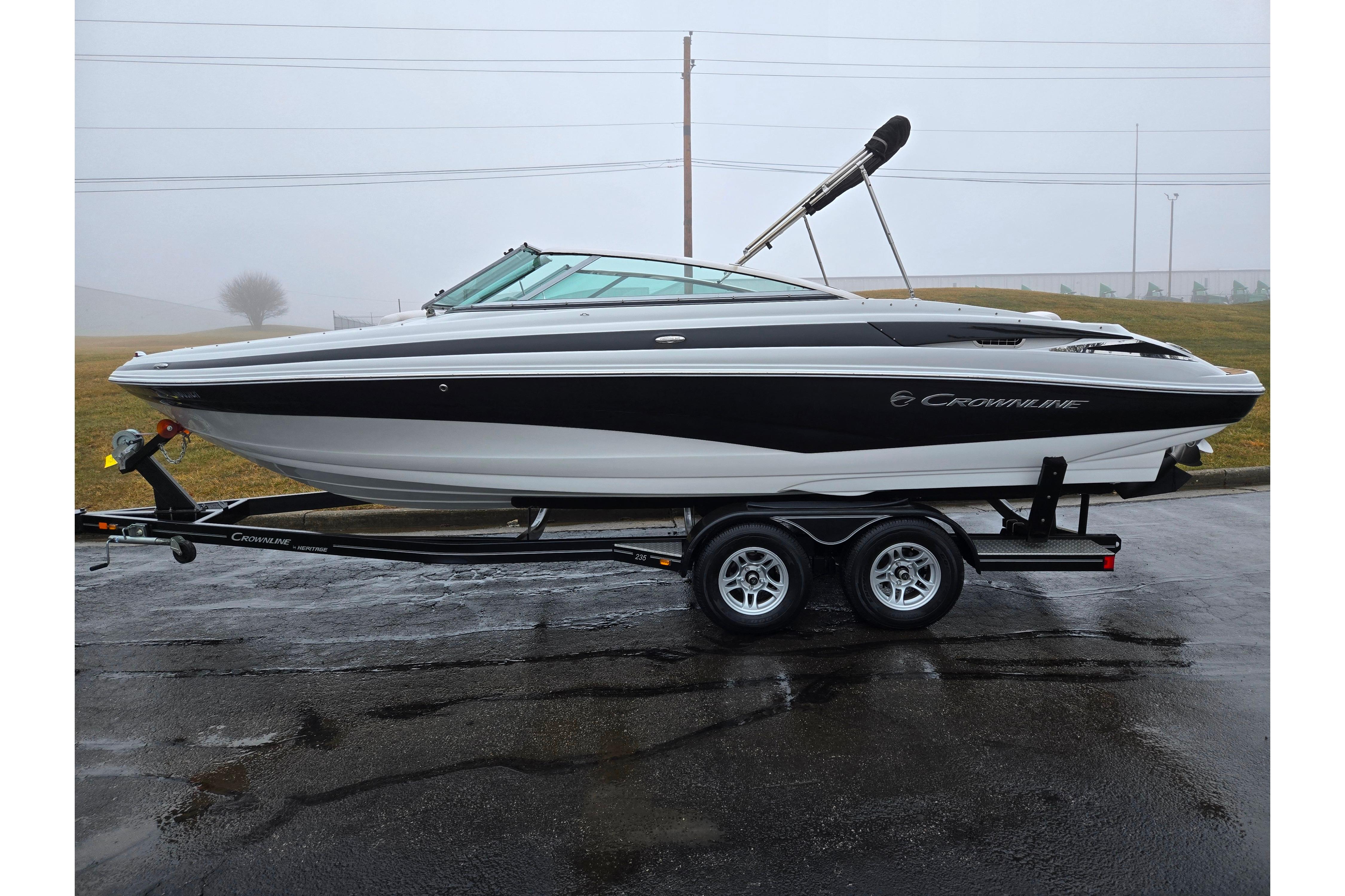 2012 Crownline 235 SS boat on trailer, parked on wet pavement in foggy weather.