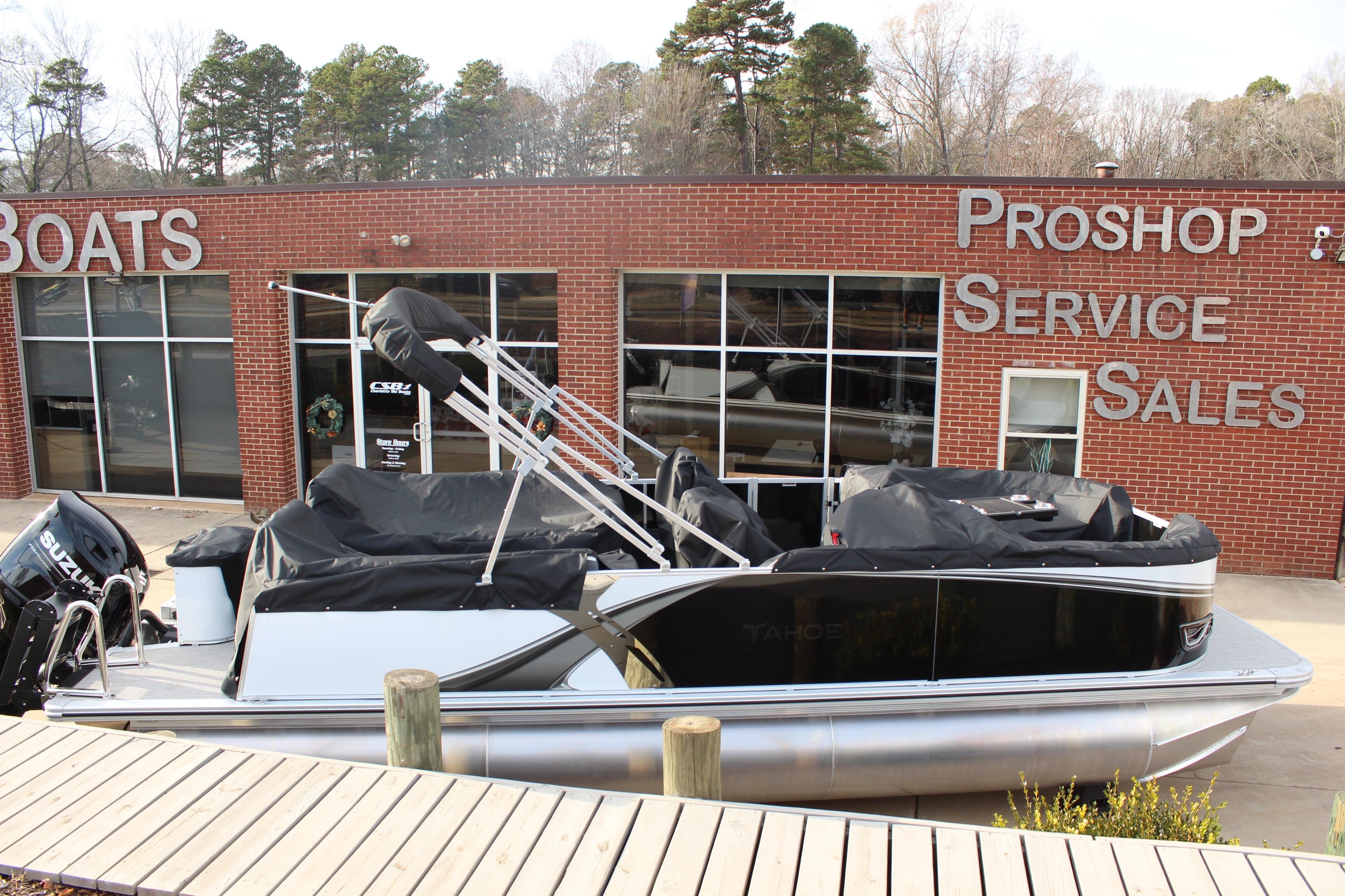 2026 Tahoe Pontoon LTZ boat displayed outside a pro shop with service and sales signage.
