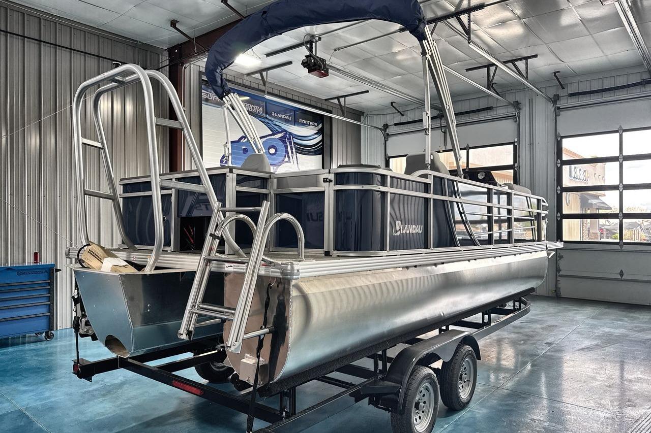 2026 Landau Island Breeze 23F pontoon boat in a garage on a trailer.