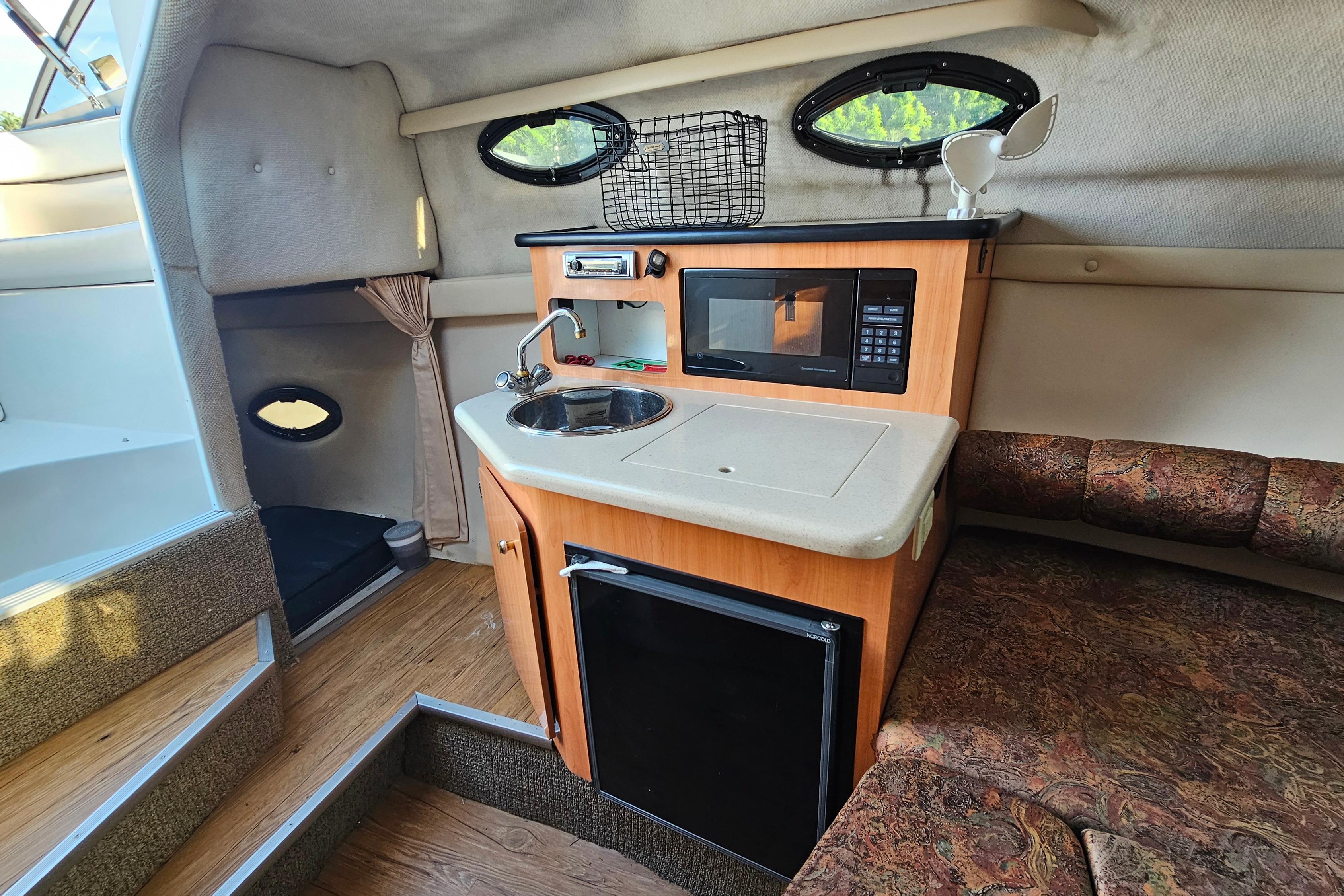 Interior of a 1999 Regal Commodore 258 boat with kitchenette and seating area.