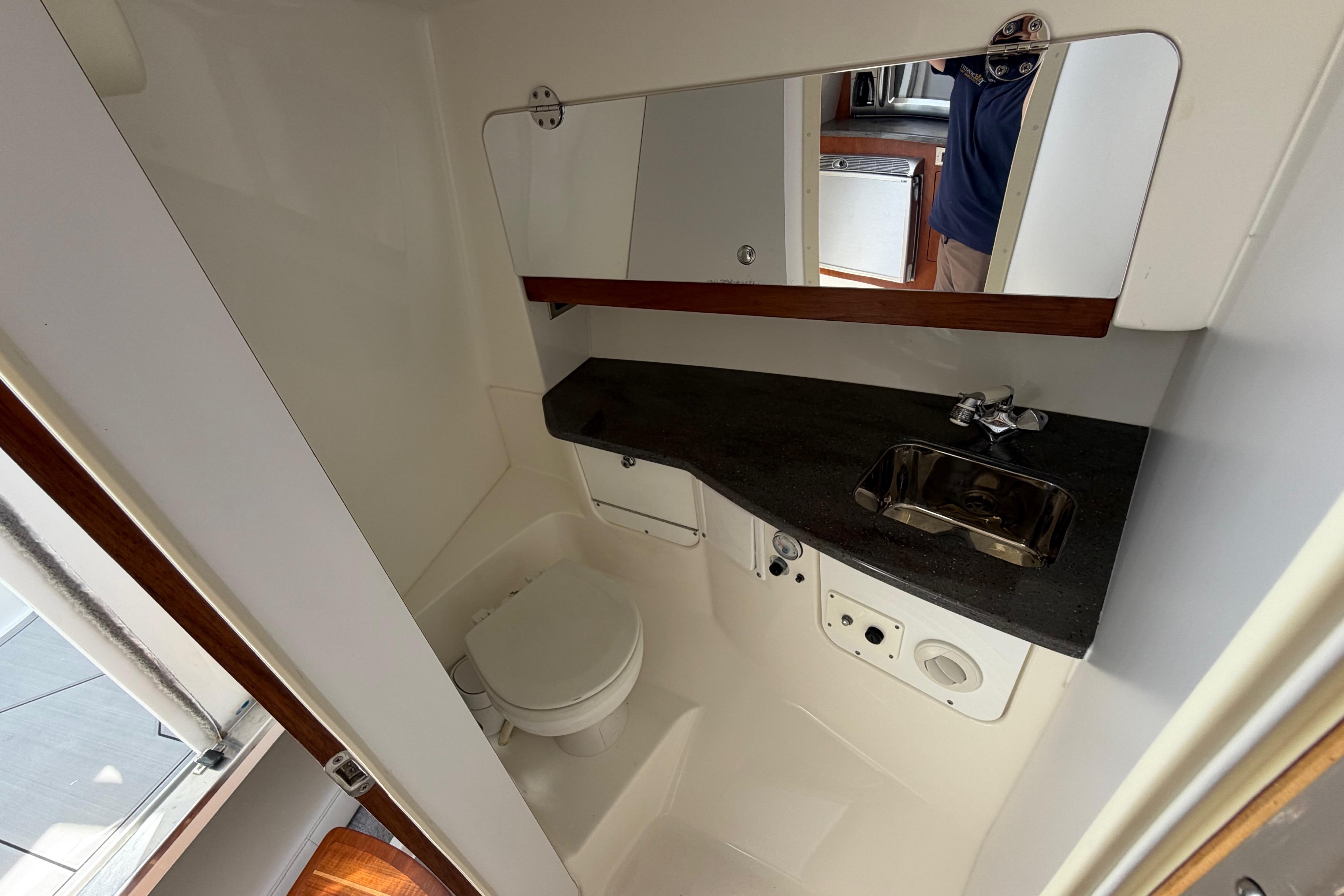 Compact bathroom in 2009 Everglades 350LX boat with sink, toilet, and mirror.