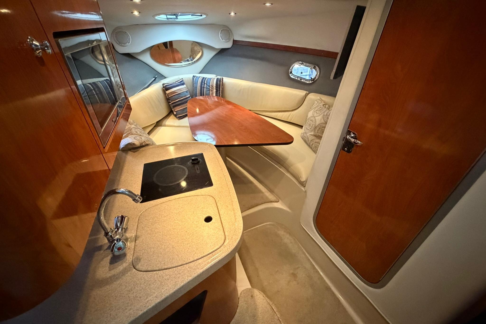 Luxurious 2008 Four Winns V248 cabin interior with kitchenette and cozy seating area.