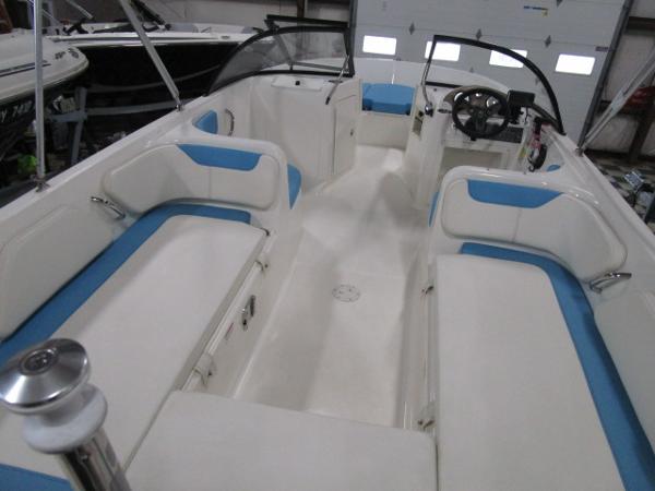 2023 Bayliner 210EL boat interior with white and blue seating, steering wheel, and open layout.
