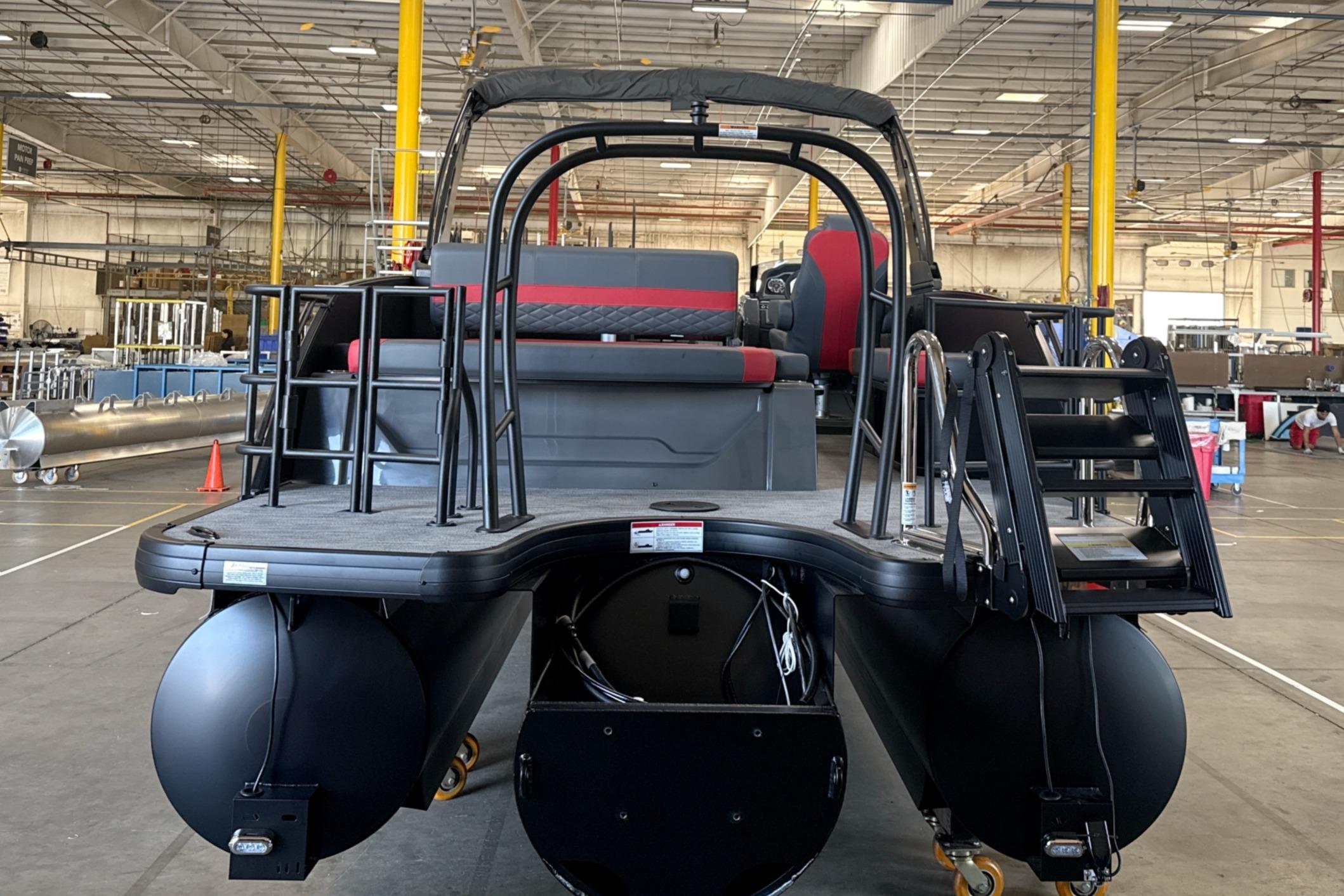 2027 Godfrey Monaco 25' Tritoon in warehouse, showcasing rear deck and seating.