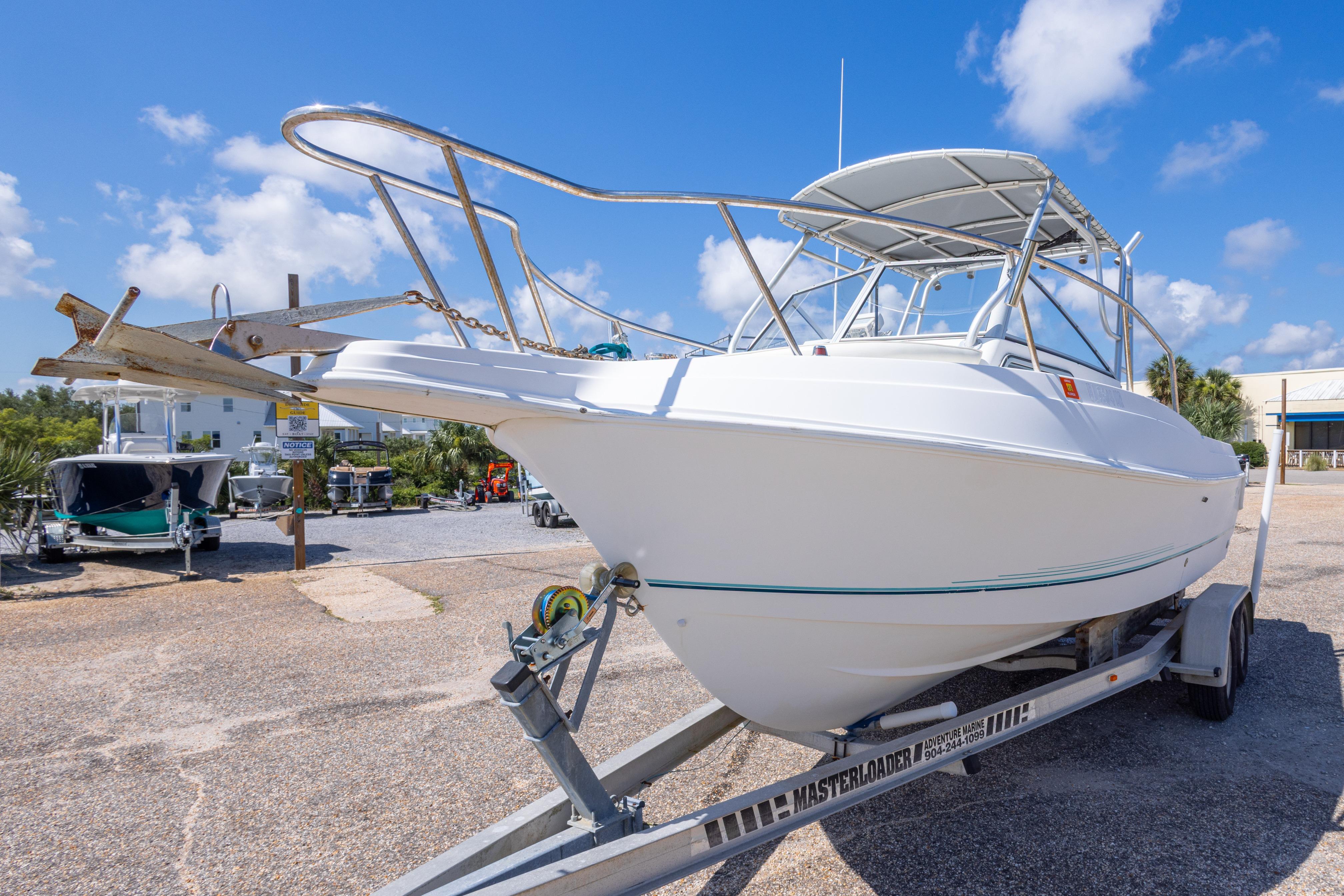 1999 Aquasport 225 Explorer boat on trailer under clear blue sky.