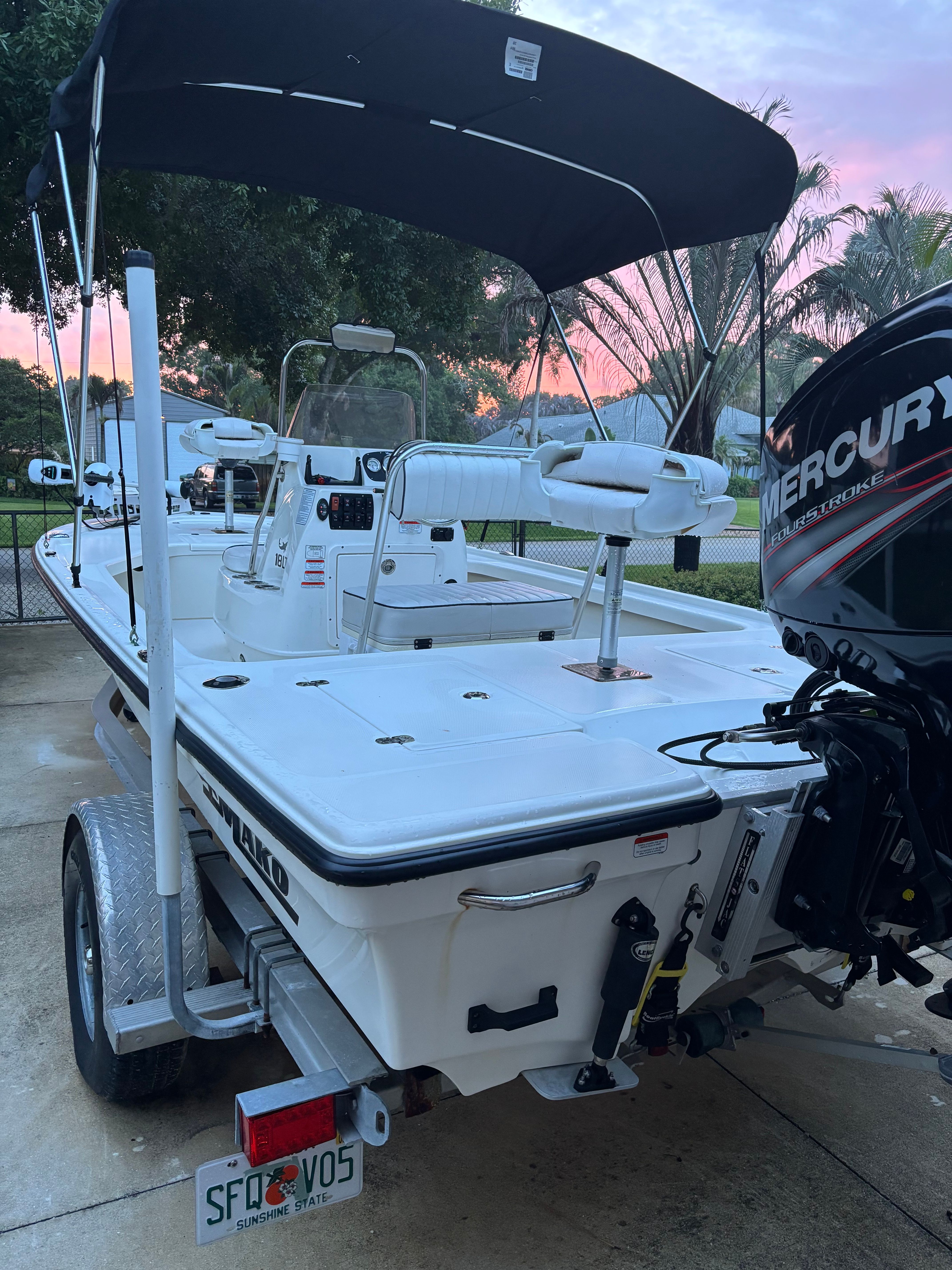 A 2016 Mako 18 LTS boat with a black sunshade, parked on a trailer.