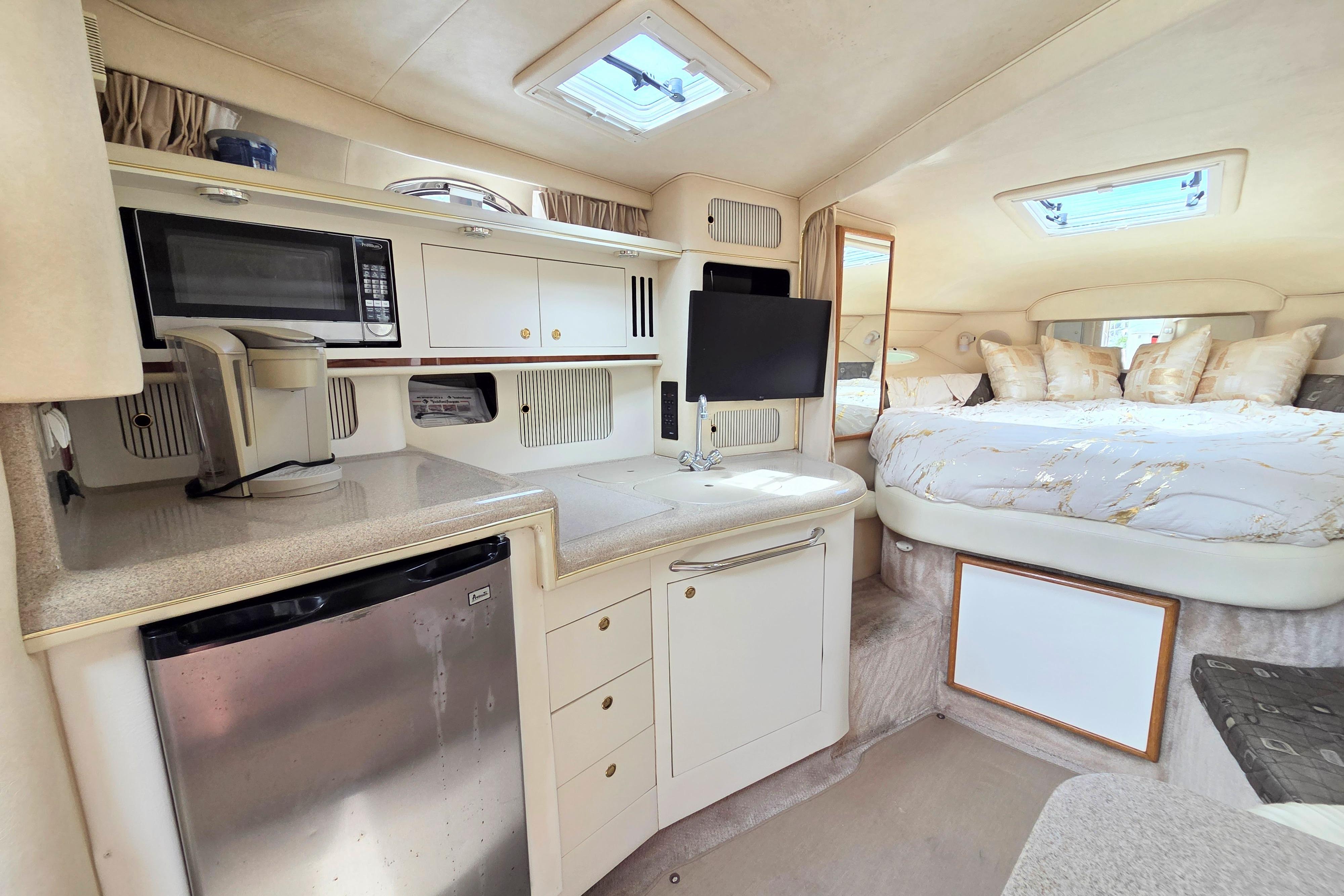 Interior of 2000 Sea Ray 340 Sundancer yacht with kitchenette and cozy sleeping area.