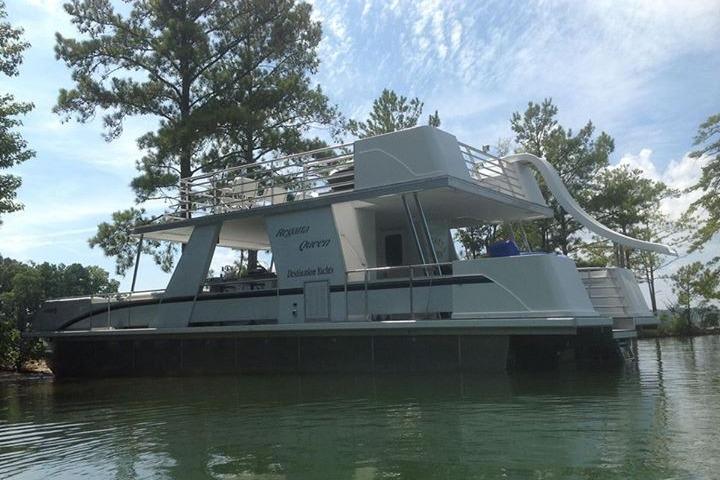 2008 Destination Yachts 45X14 houseboat with slide, docked on a serene lake.