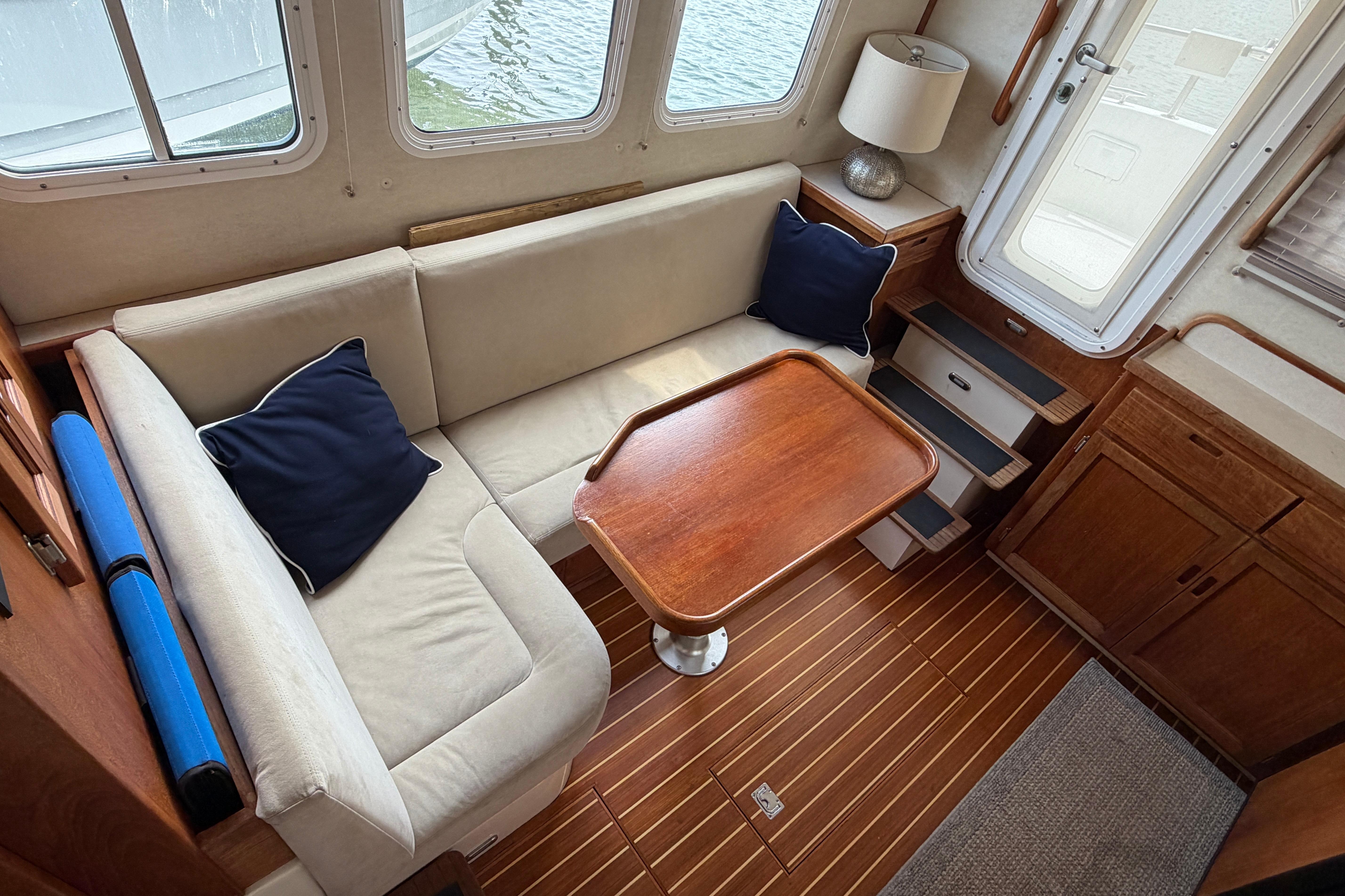 Cozy interior of 2007 Nordic Tug 32 with beige seating and wooden table.