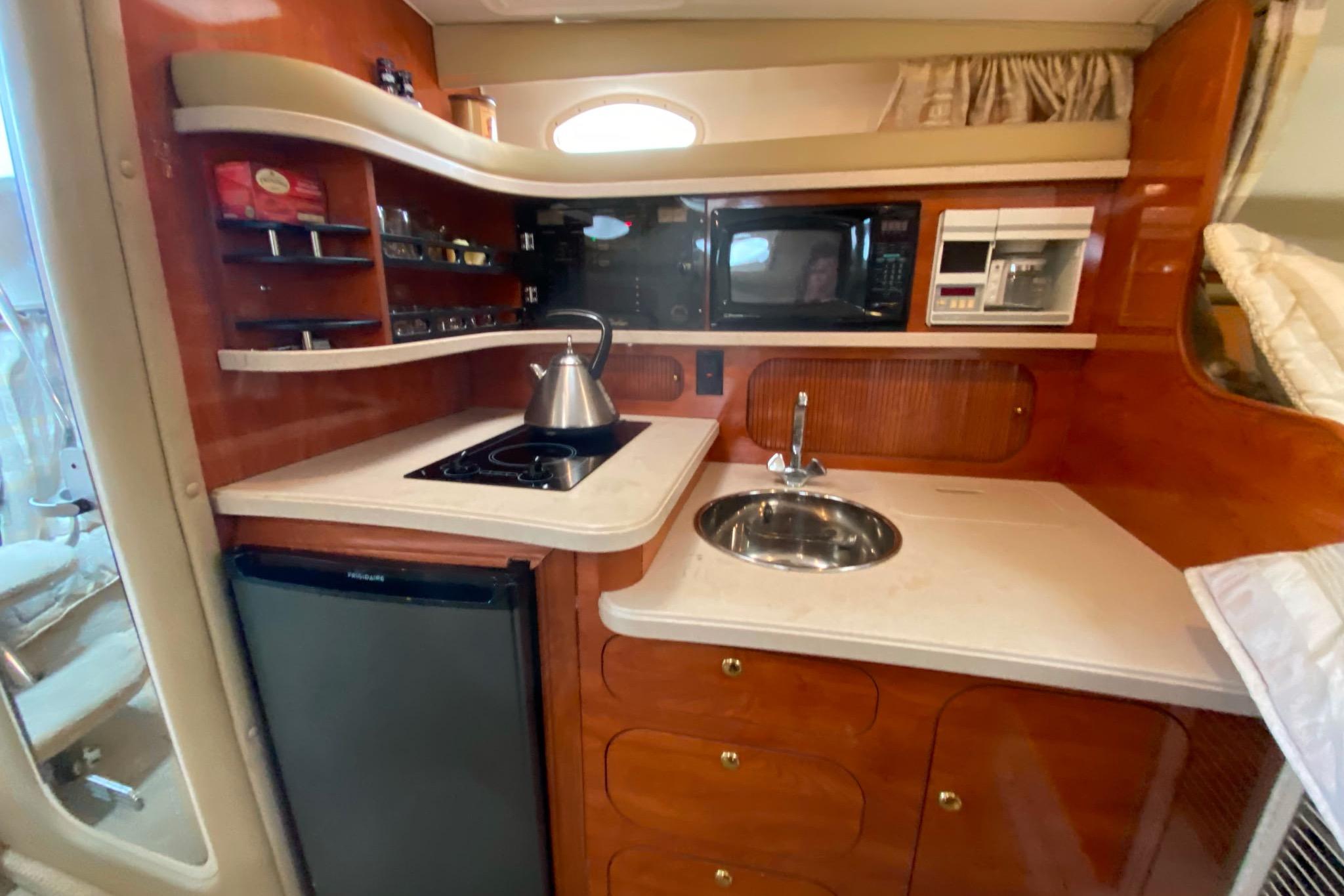 2003 Rinker Fiesta Vee 342 boat kitchen with stove, sink, and microwave.