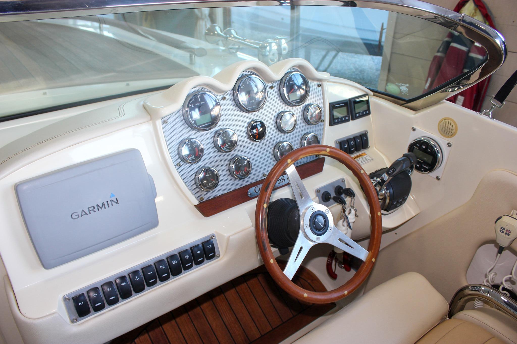 2011 Chris-Craft Corsair 28 dashboard with Garmin navigation and classic wooden steering wheel.