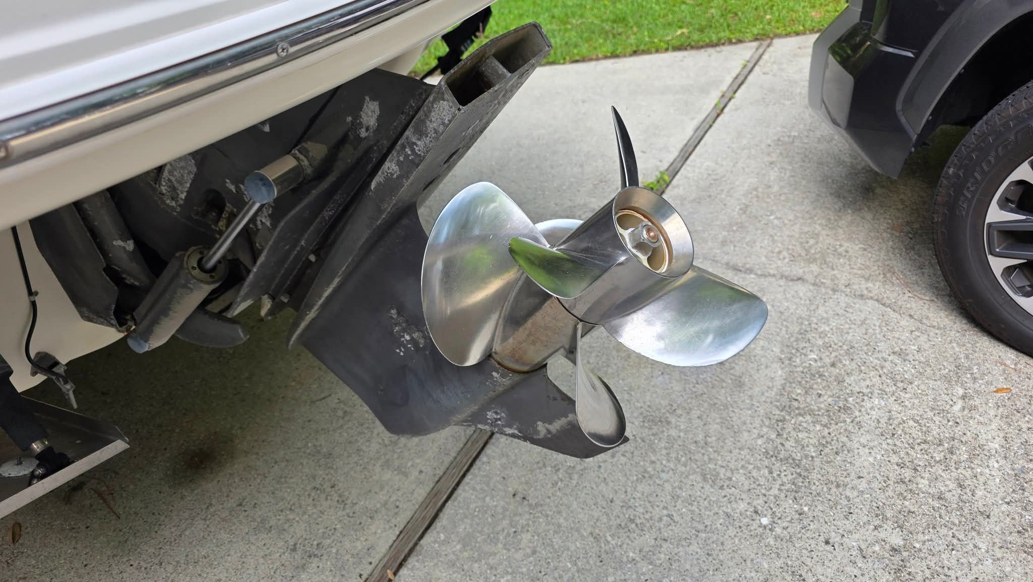 Close-up of a shiny propeller on a boat, resting on a concrete surface.