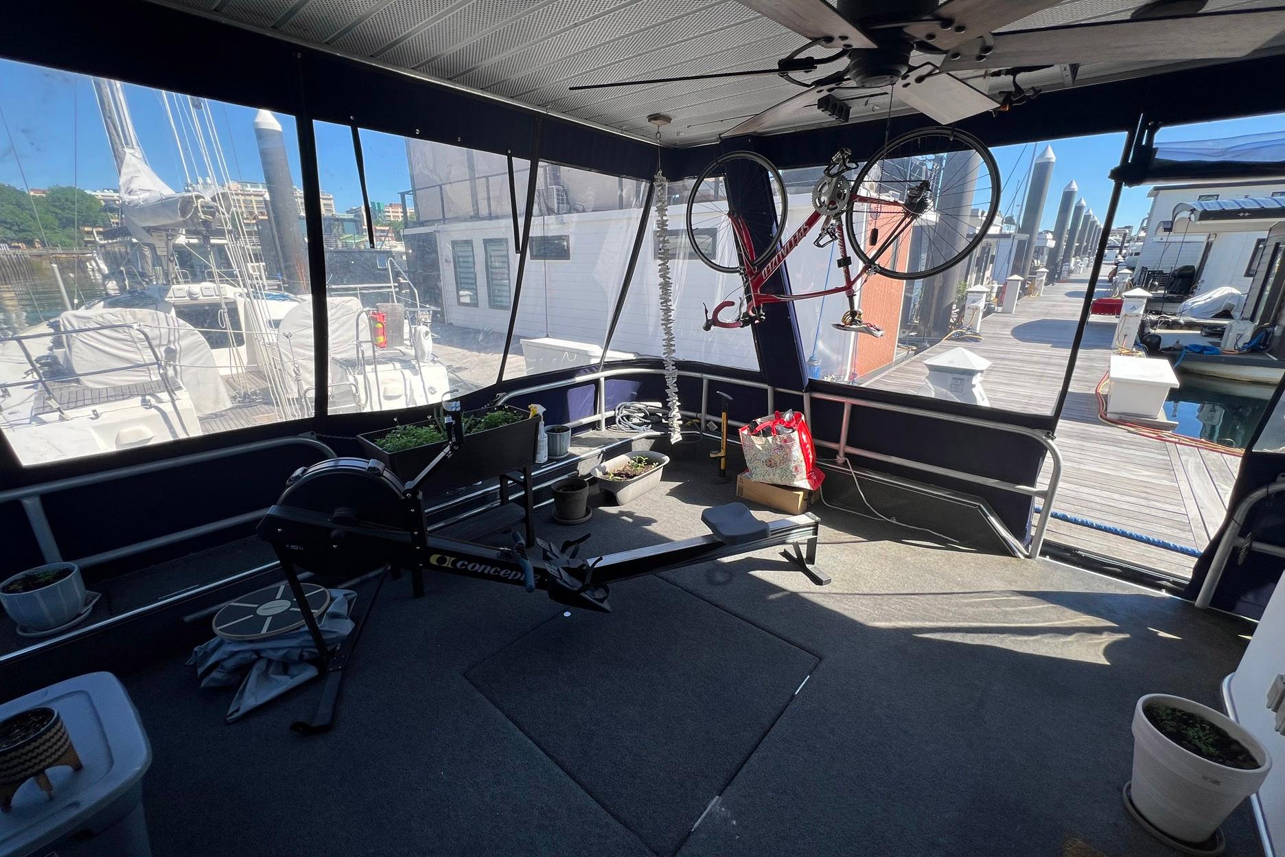 1993 Sumerset houseboat interior with exercise equipment and bicycle, docked at a marina.
