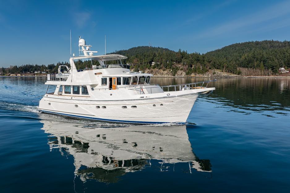 2009 Selene 60 Ocean Trawler cruising on calm waters with forested shoreline backdrop.